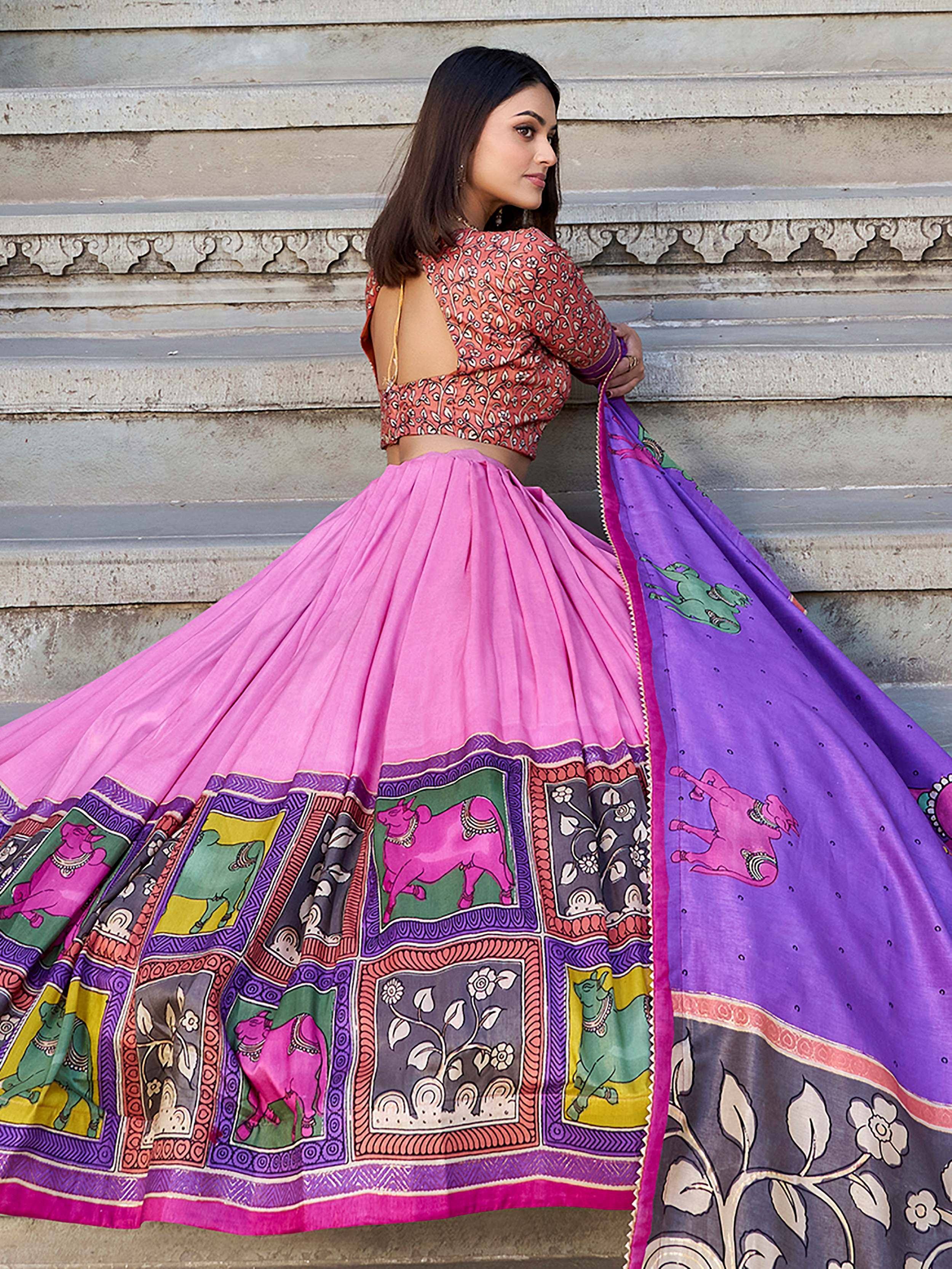 Woman in vibrant pink and purple printed lehenga choli with traditional Indian motifs, perfect for ethnic occasions.