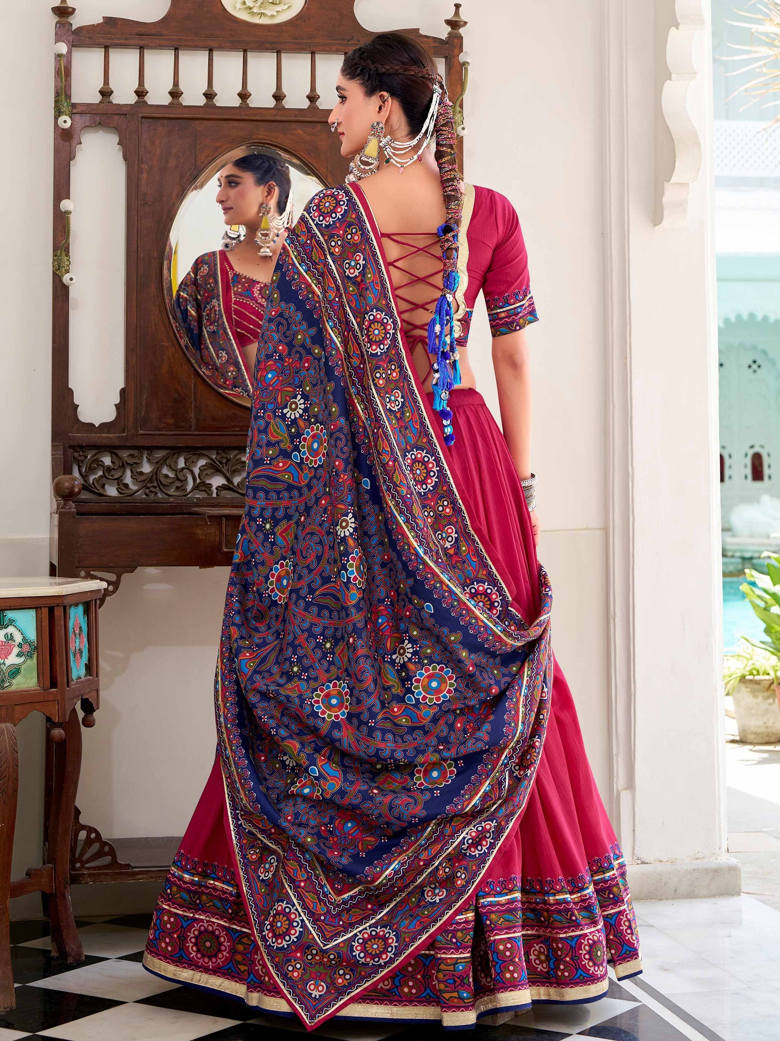 Woman in vibrant Indian ethnic lehenga choli with floral print dupatta, traditional jewelry, and mirror backdrop