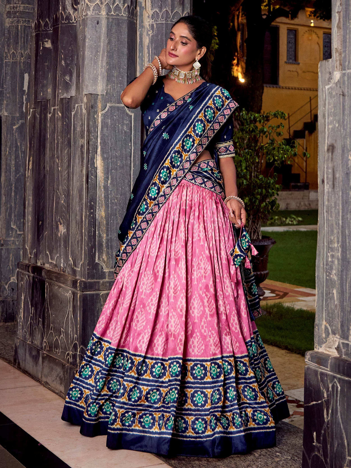 Woman in navy blue and pink designer lehenga choli with intricate embroidery, perfect for Indian ethnic wear occasions.
