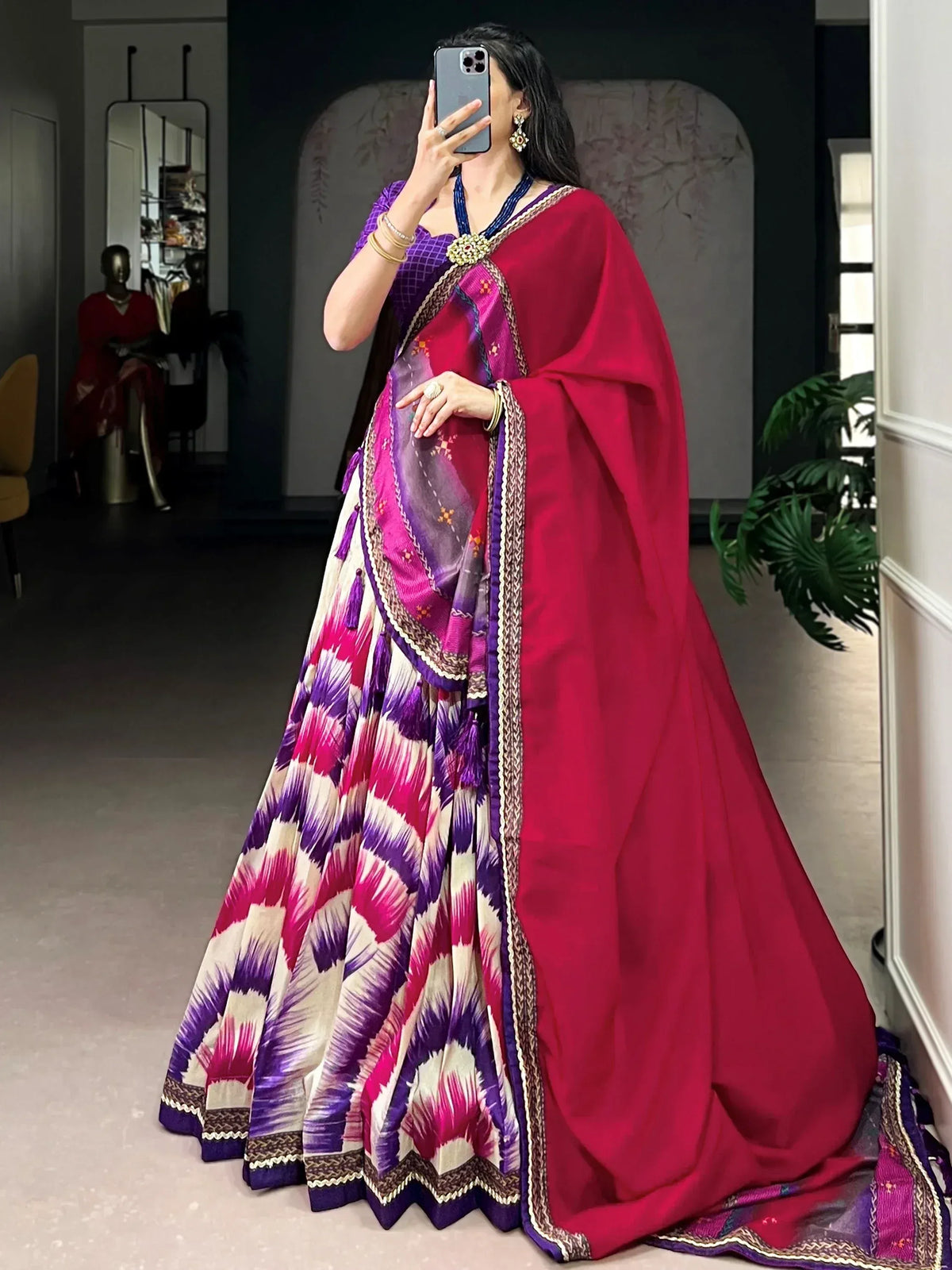 Woman in vibrant purple and pink ikat print lehenga choli with red dupatta, perfect for Indian ethnic wear occasions