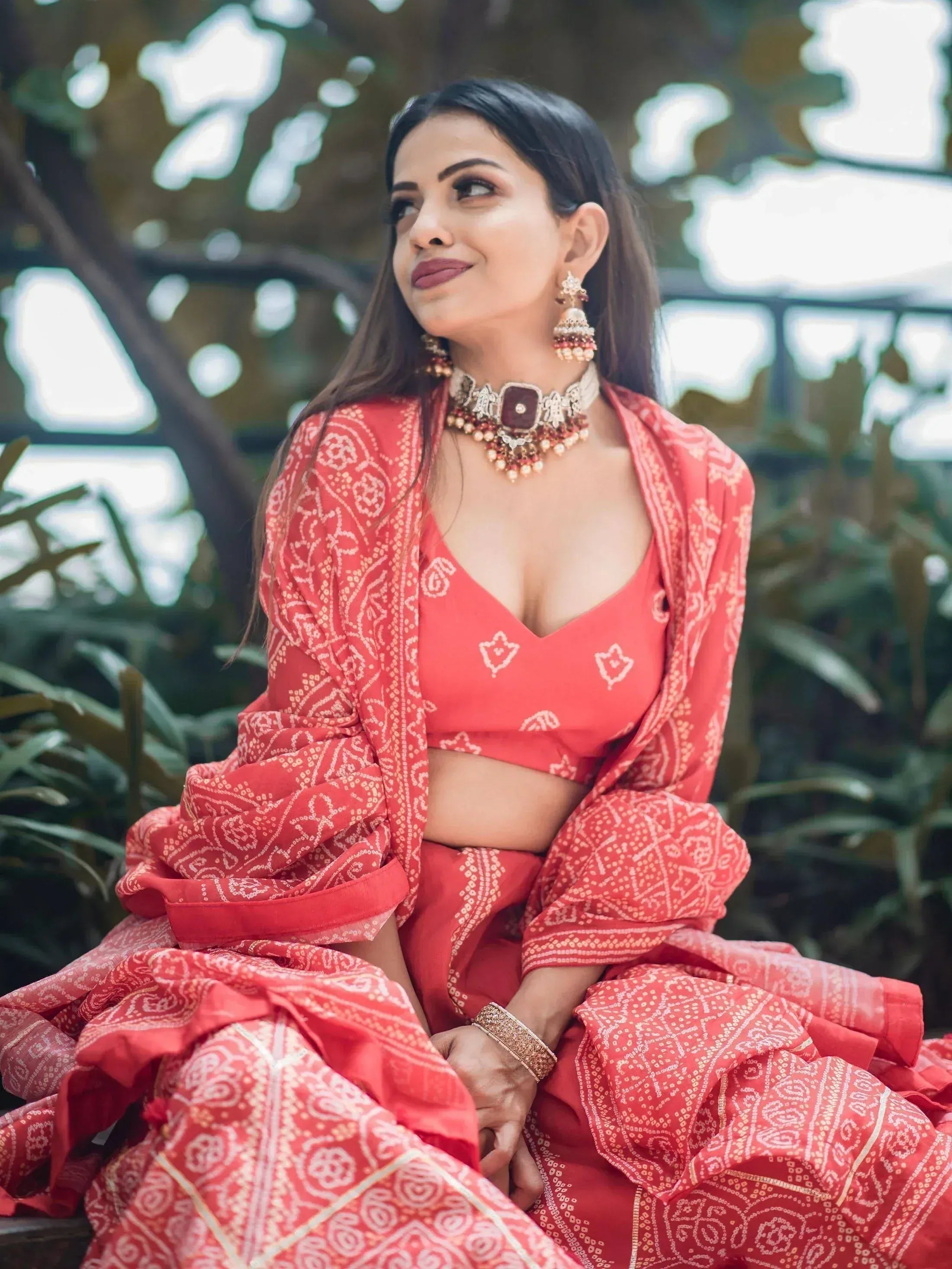 Woman in red printed lehenga choli with traditional jewelry, perfect for Indian ethnic wear occasions