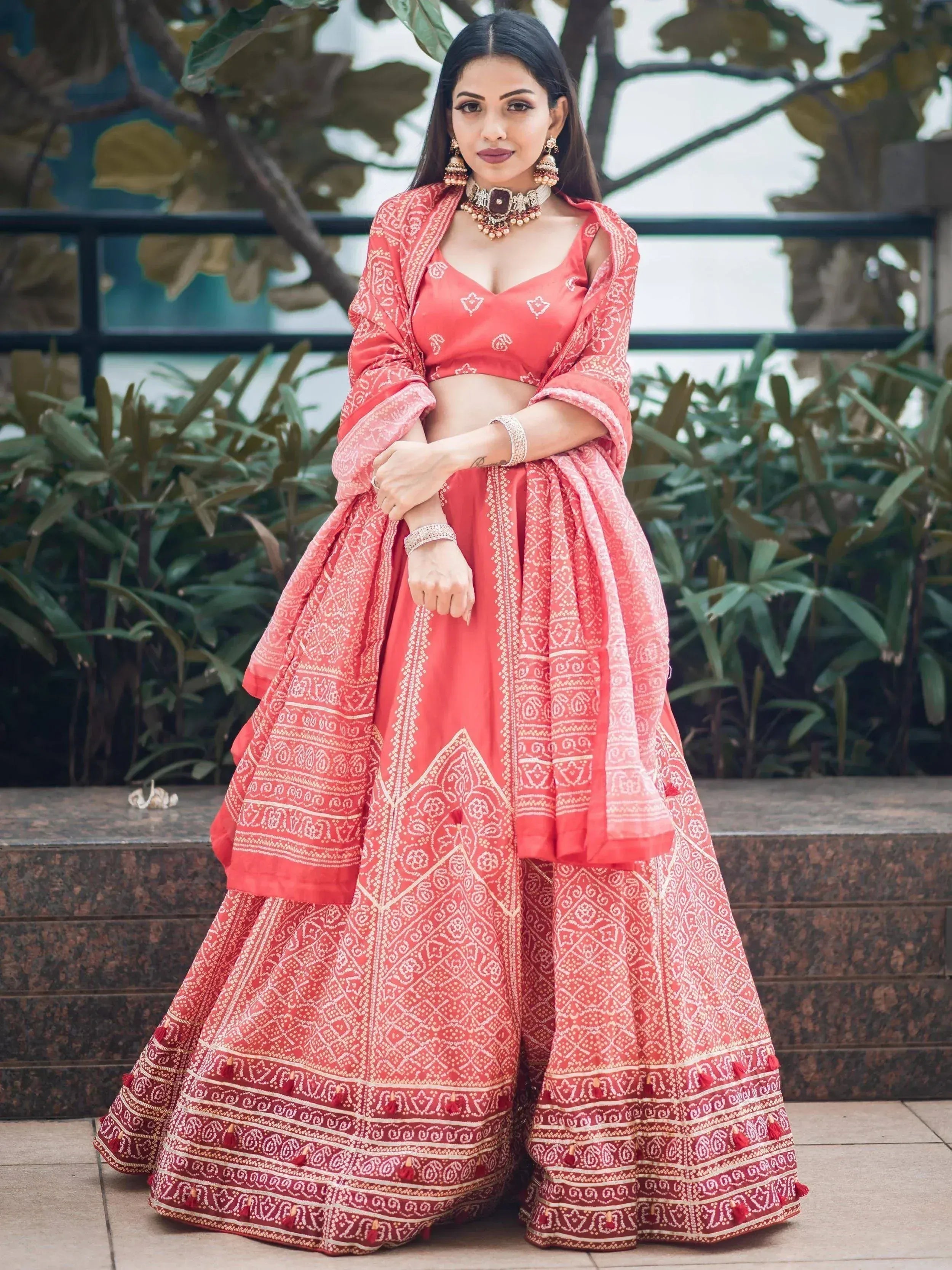 Woman in coral printed lehenga choli with dupatta, traditional Indian ethnic wear for weddings and festivals
