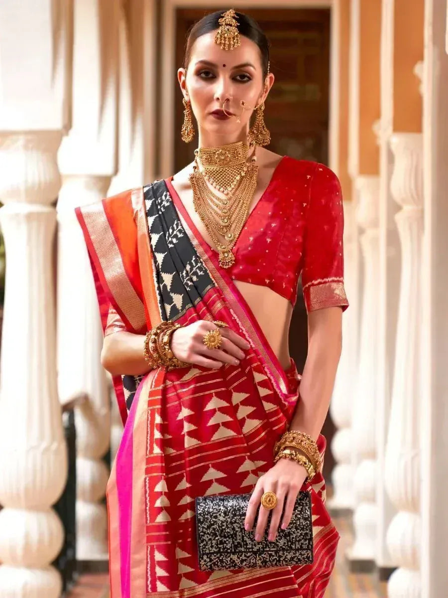 Red ethnic saree with geometric print, gold jewelry, and designer blouse for Indian occasions