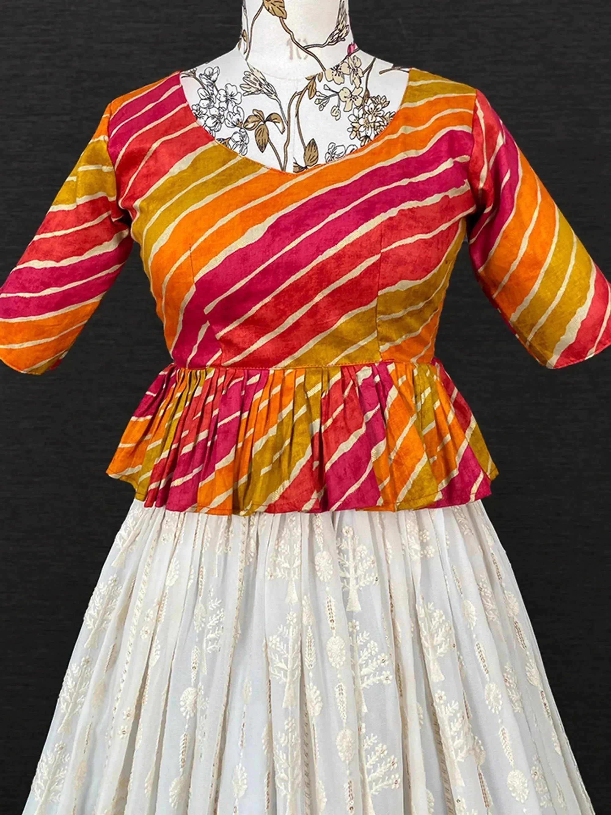 Vibrant striped ethnic top with peplum waist paired with white embroidered skirt, perfect for festive occasions.