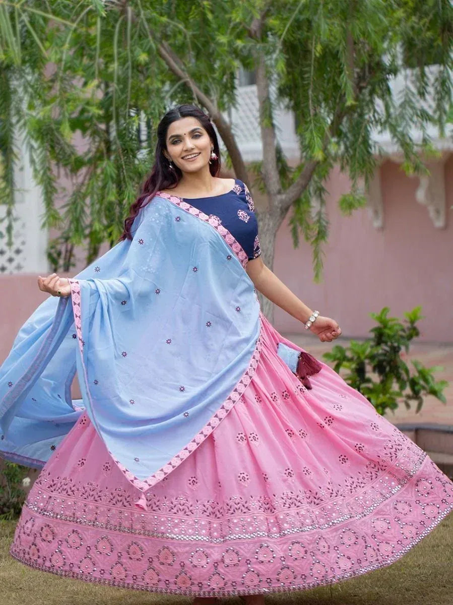 Woman in pink embroidered lehenga choli with blue dupatta, twirling outdoors