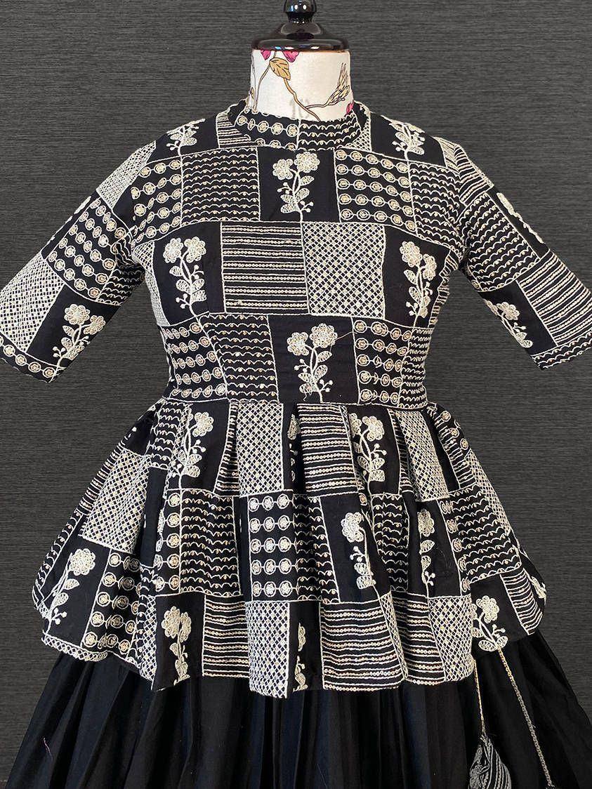 Black and white embroidered ethnic gown with patchwork design, floral motifs, and flared peplum top