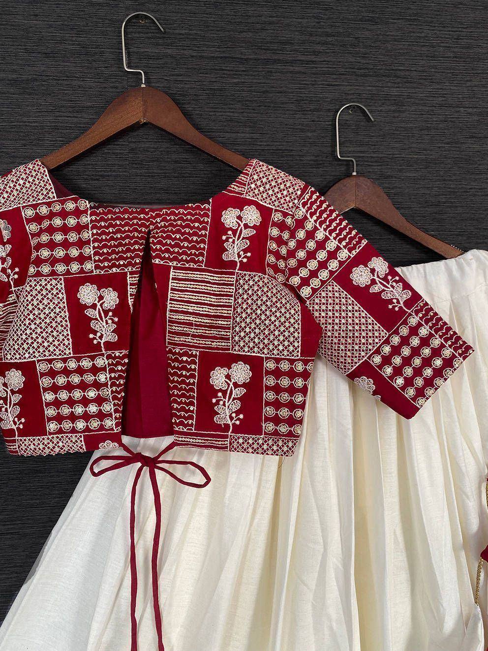 Red embroidered crop top with white floral patterns paired with cream skirt, ethnic wear