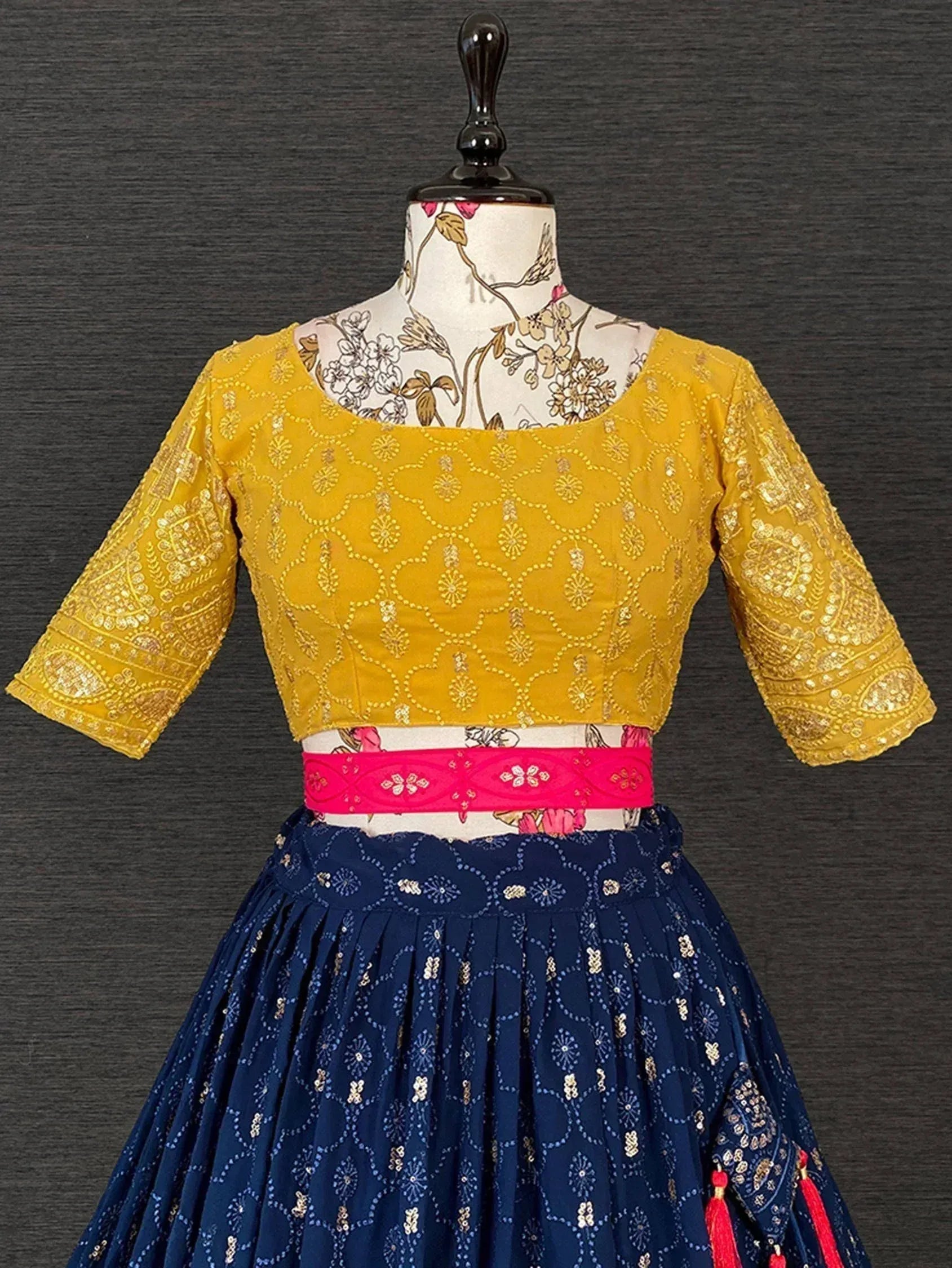 Yellow embroidered blouse with navy blue lehenga, pink waistband, and tassels for Indian ethnic wear