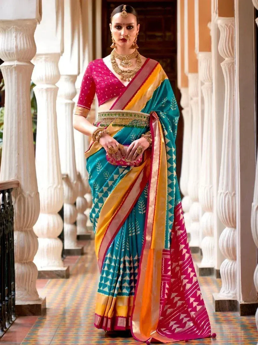 Woman in vibrant ethnic saree with pink blouse, gold jewelry, standing in traditional Indian corridor