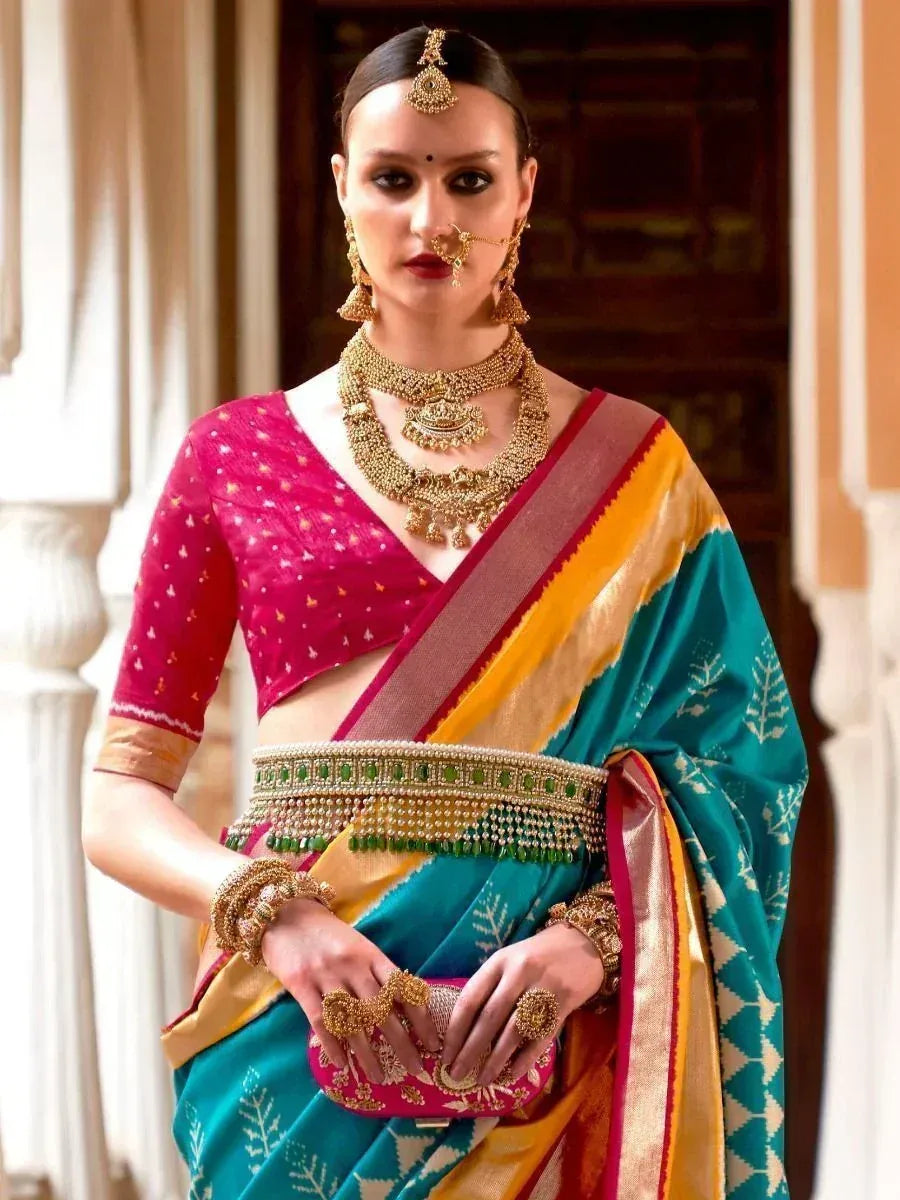 Woman in vibrant teal and pink saree with gold jewelry, traditional Indian ethnic wear