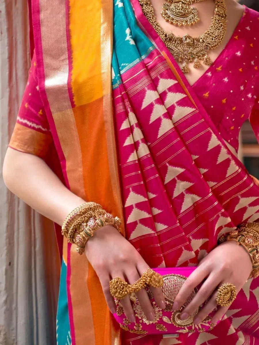 Vibrant pink ikat saree with gold jewelry, perfect for Indian ethnic wear occasions
