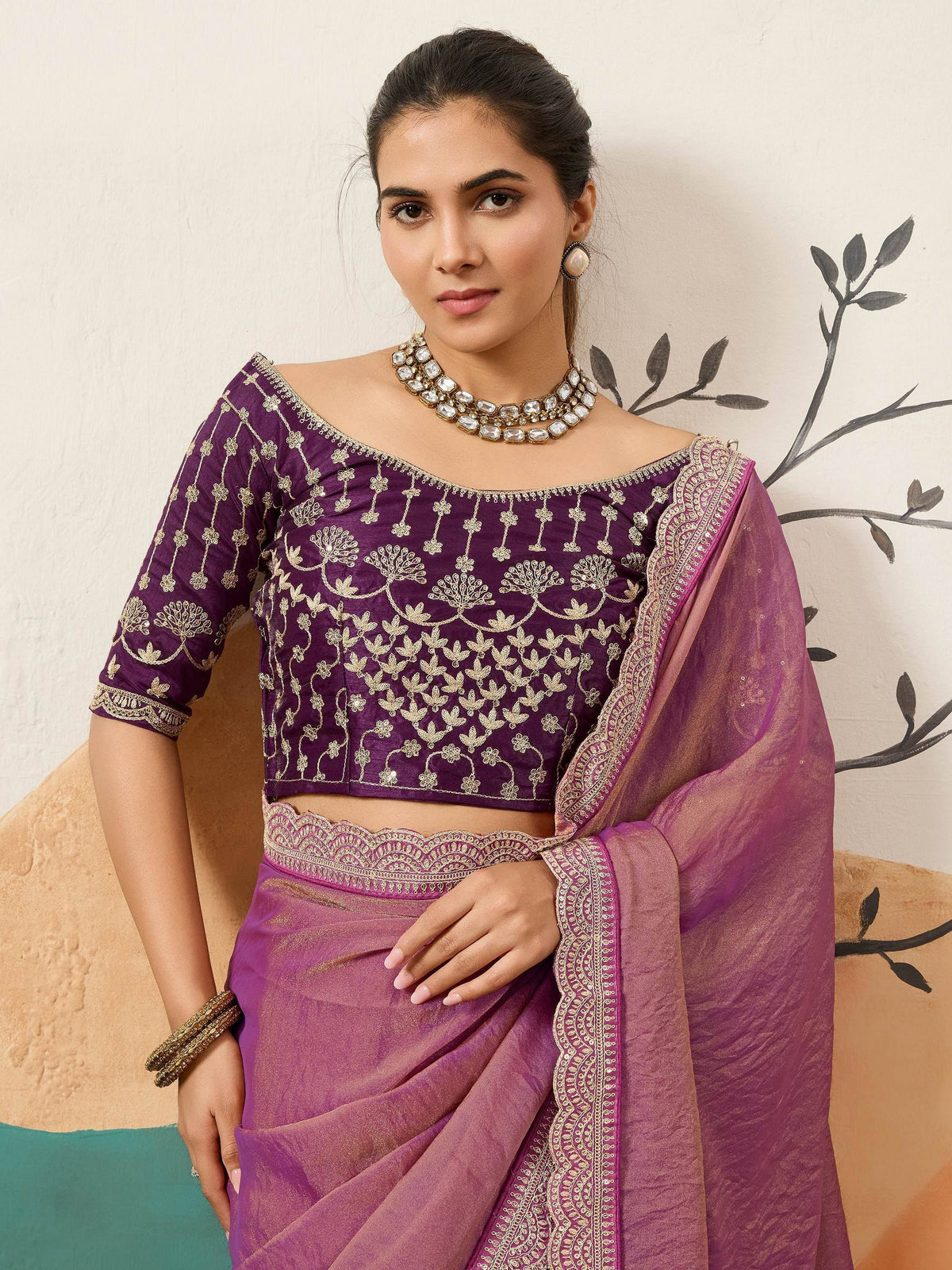 Purple embroidered saree with gold floral work, off-shoulder blouse, and statement jewelry for ethnic wear