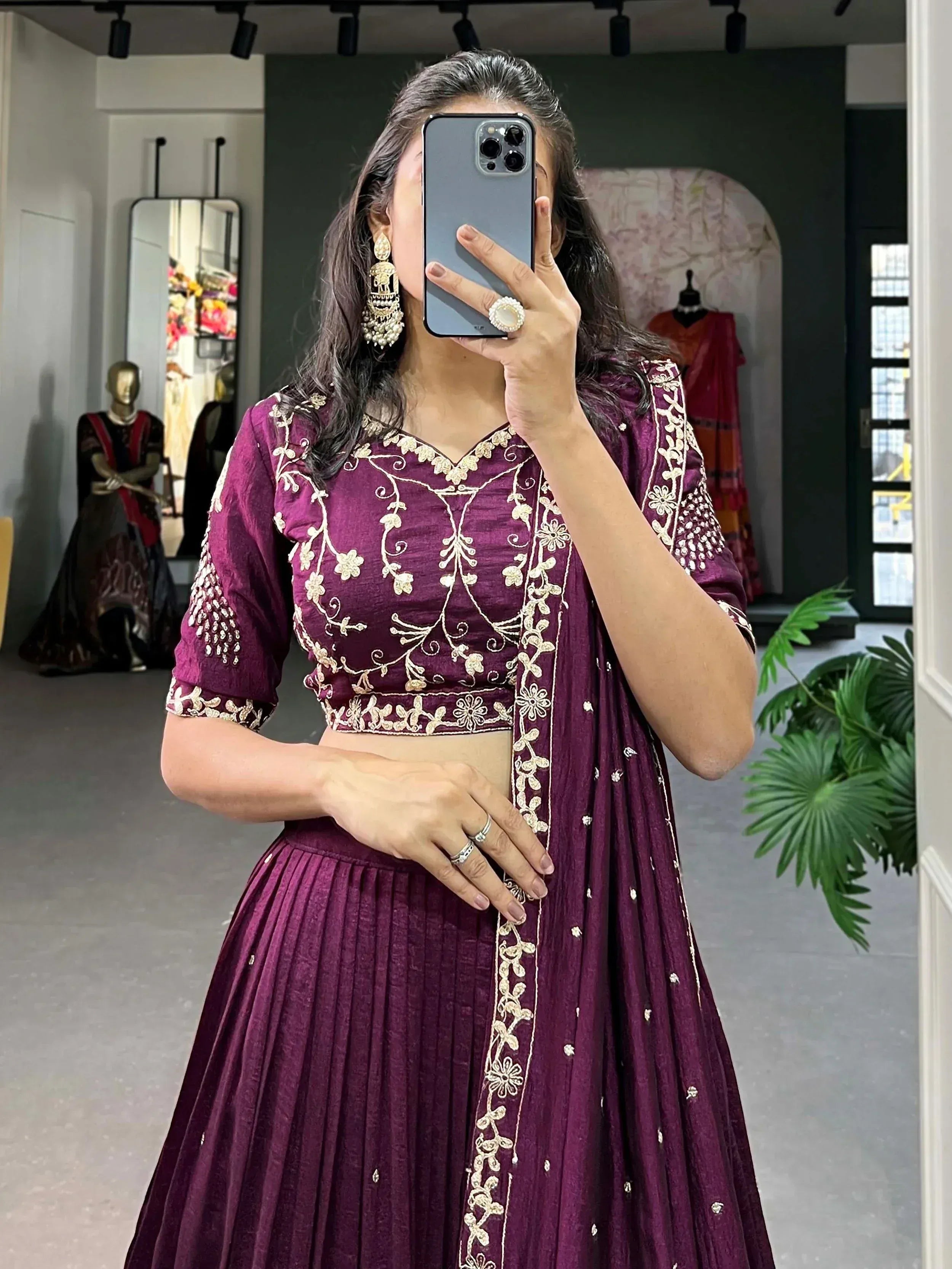 Woman in purple embroidered lehenga choli taking mirror selfie, ethnic Indian wear with gold floral detailing
