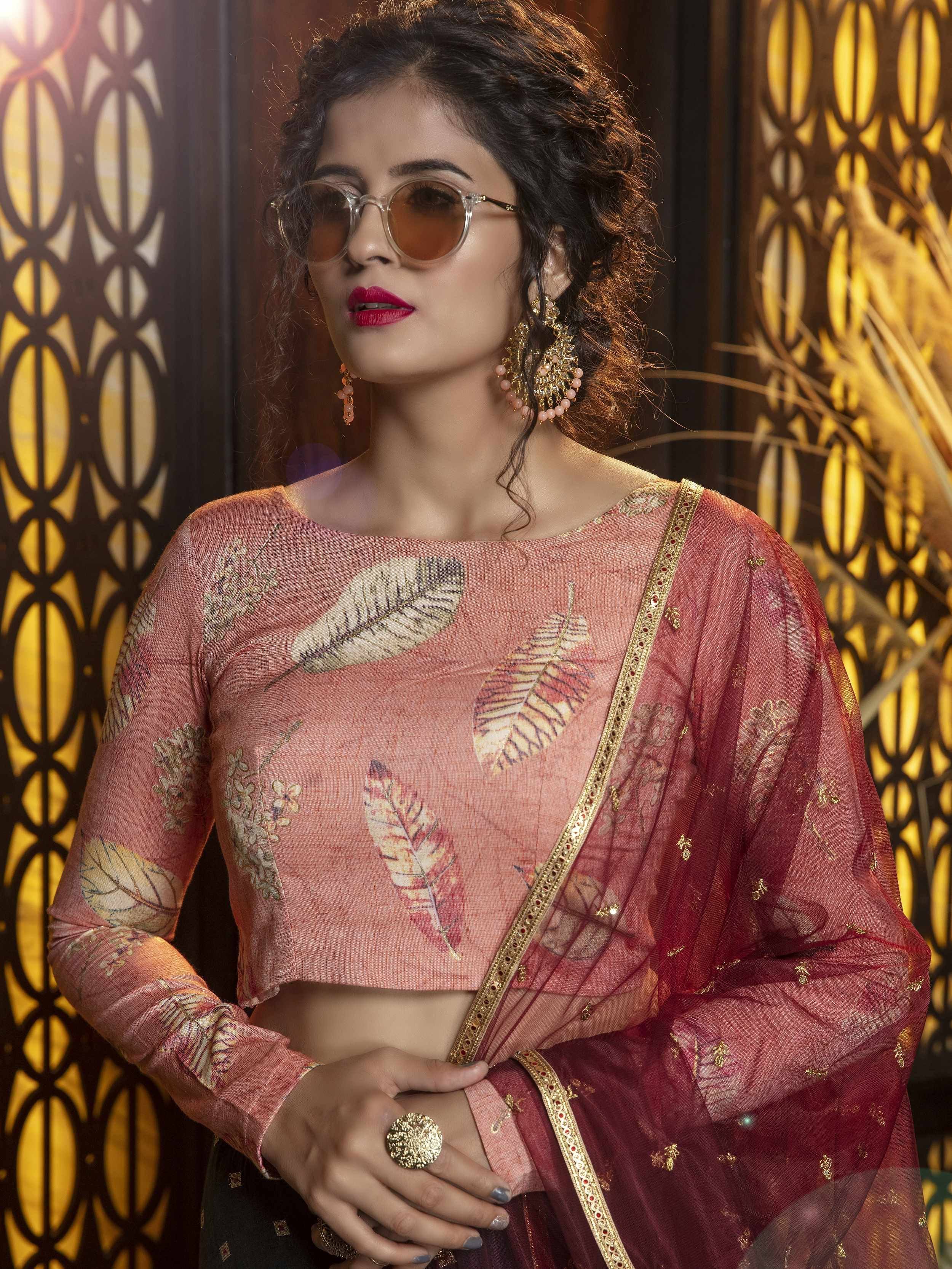 Woman in pink leaf-print ethnic crop top with sheer dupatta, gold embroidery, and statement earrings