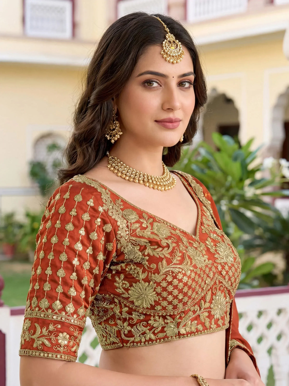 Elegant Indian ethnic blouse with gold embroidery, paired with traditional jewelry for festive occasions.