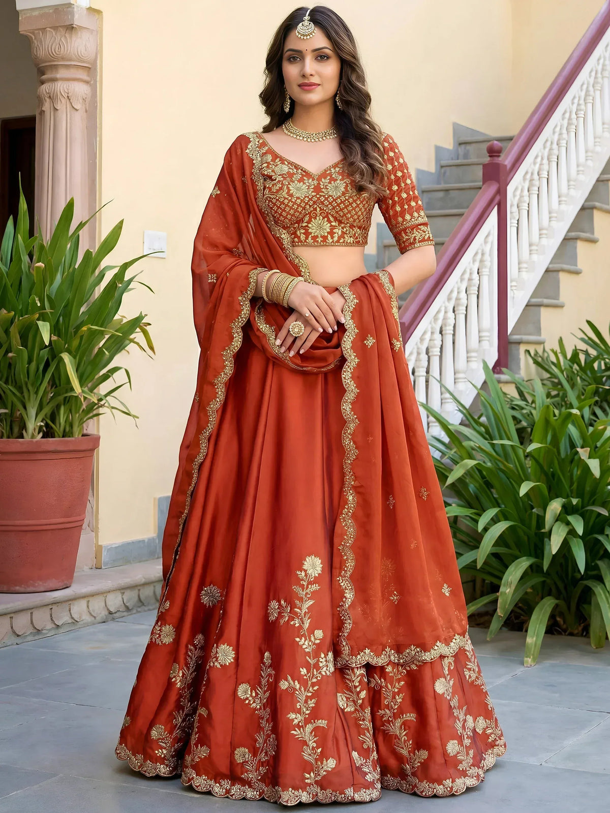 Rust orange designer lehenga choli with gold floral embroidery, perfect for weddings and festive occasions.