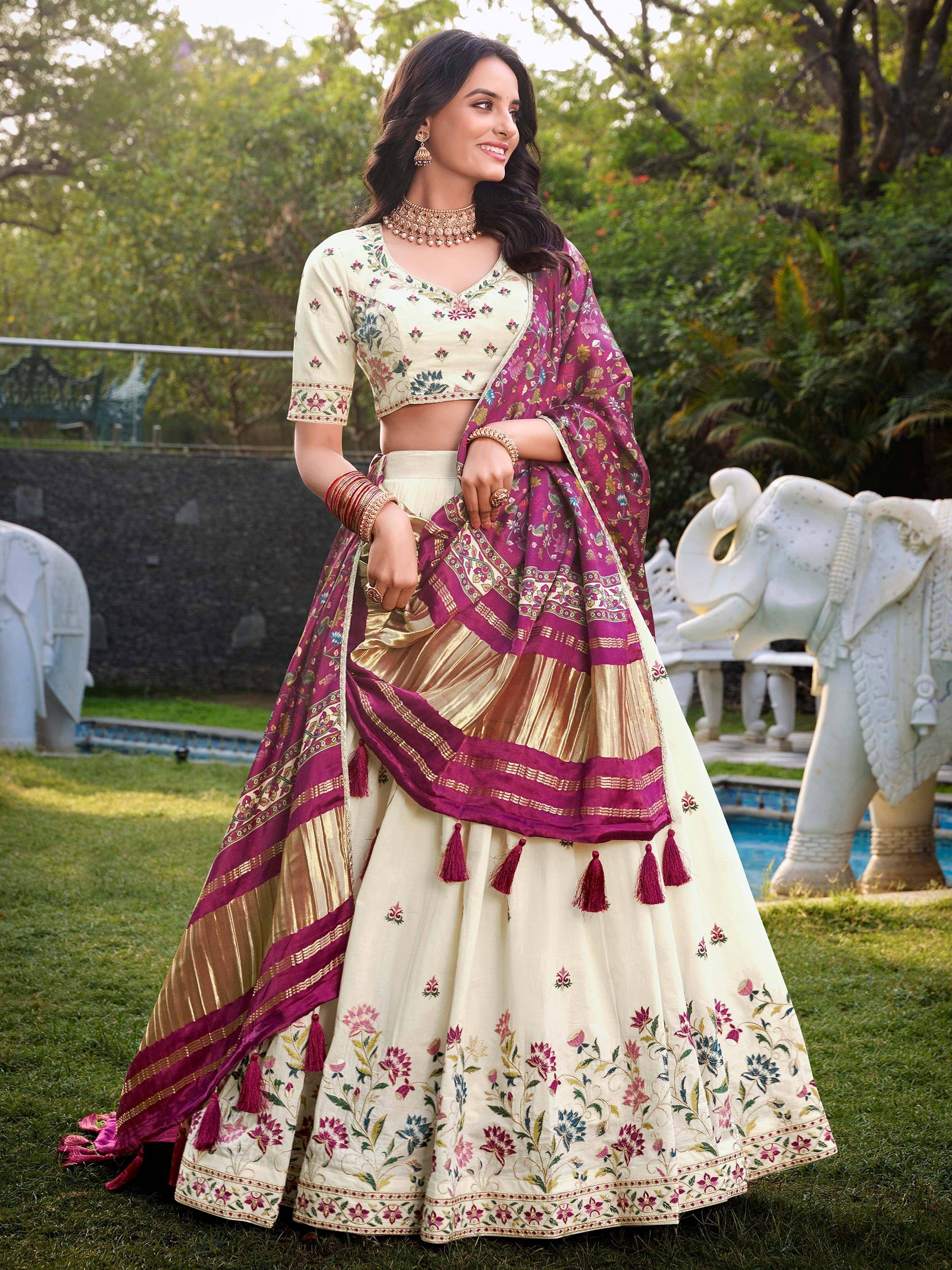 Elegant cream and magenta embroidered lehenga choli with floral motifs and tassels, perfect for Indian ethnic occasions.