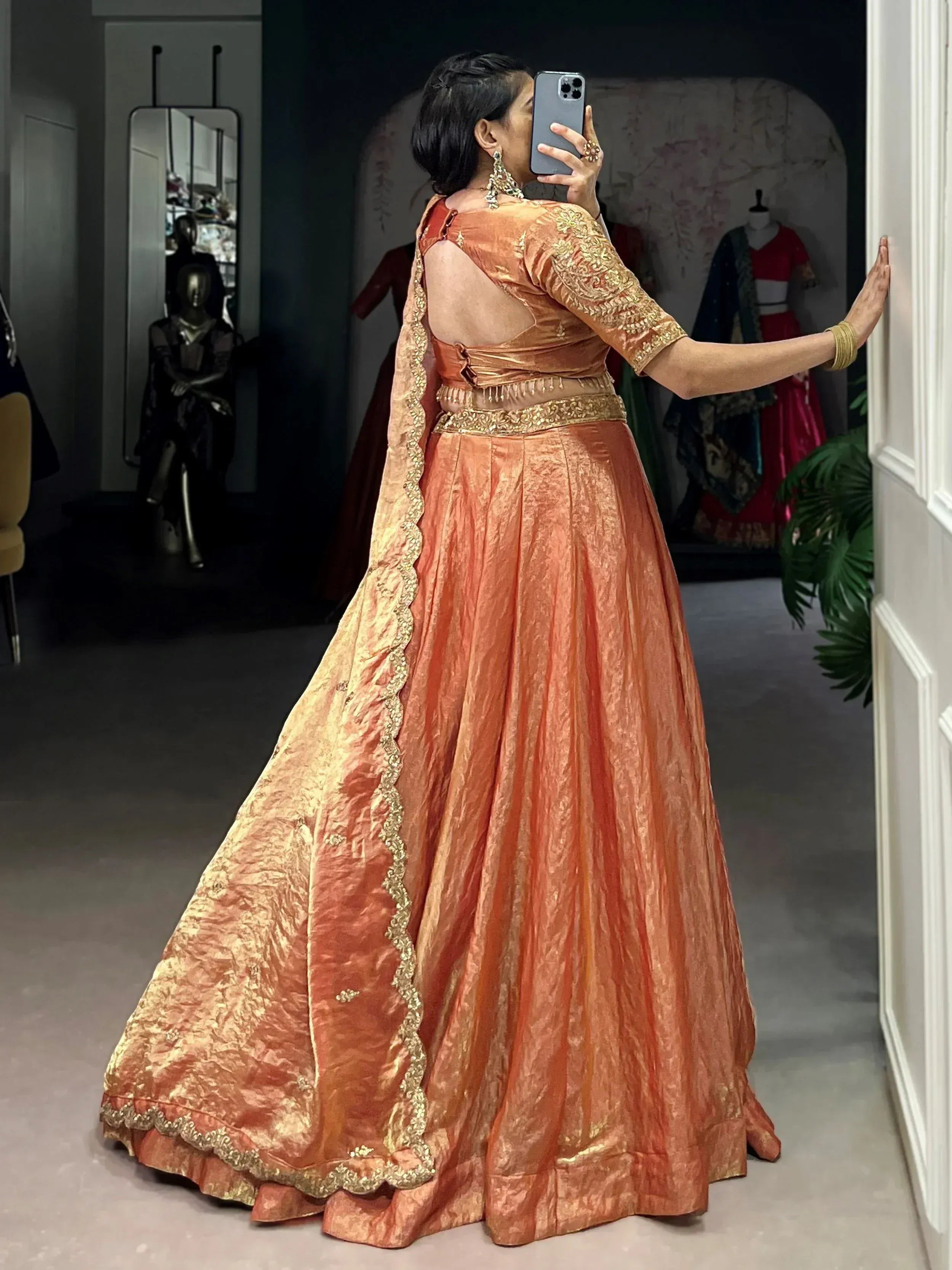 Woman taking mirror selfie in peach designer lehenga choli with gold embroidery, perfect for Indian ethnic wear occasions