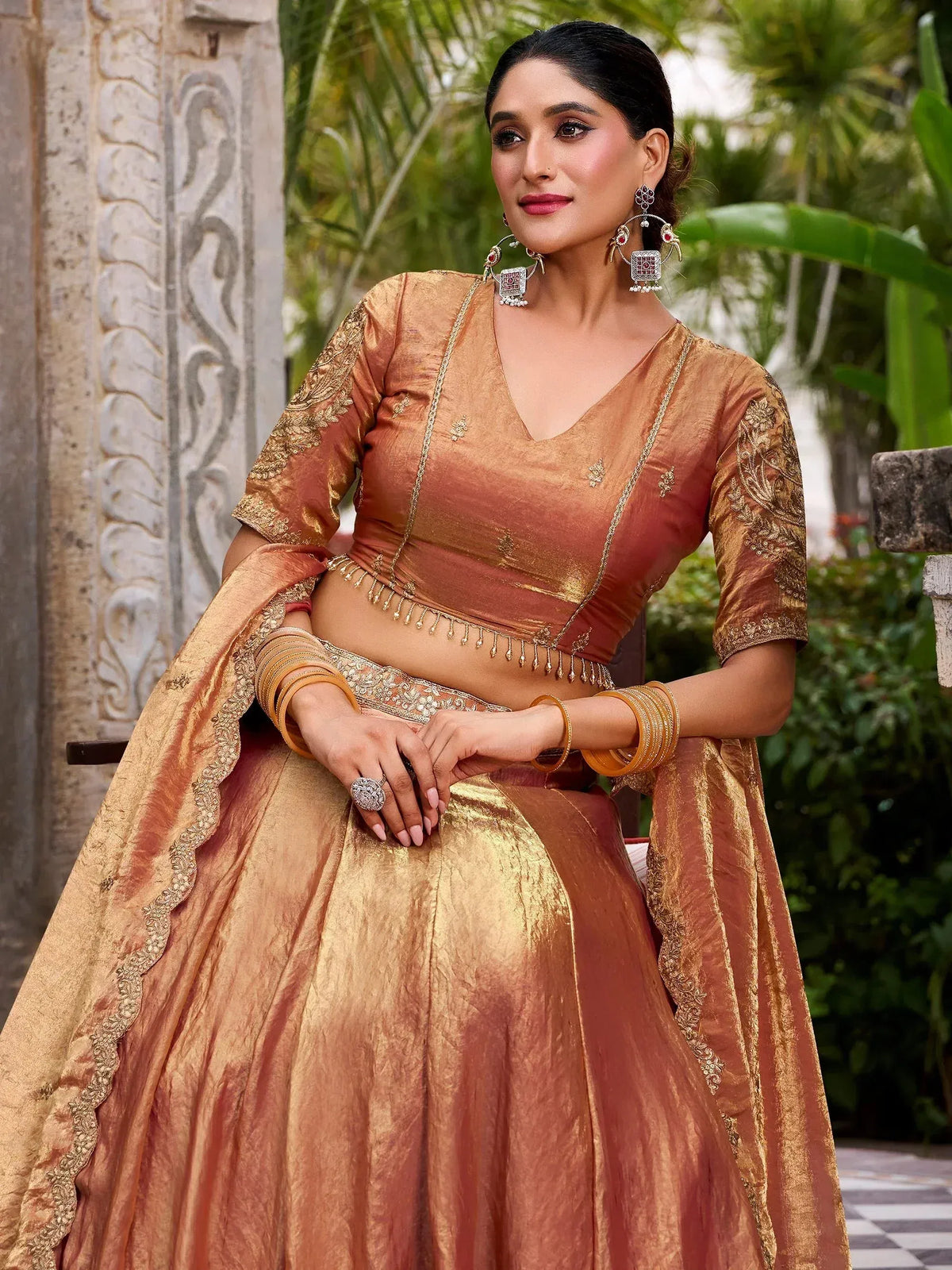 Elegant gold and peach designer lehenga choli with intricate embroidery and traditional jewelry