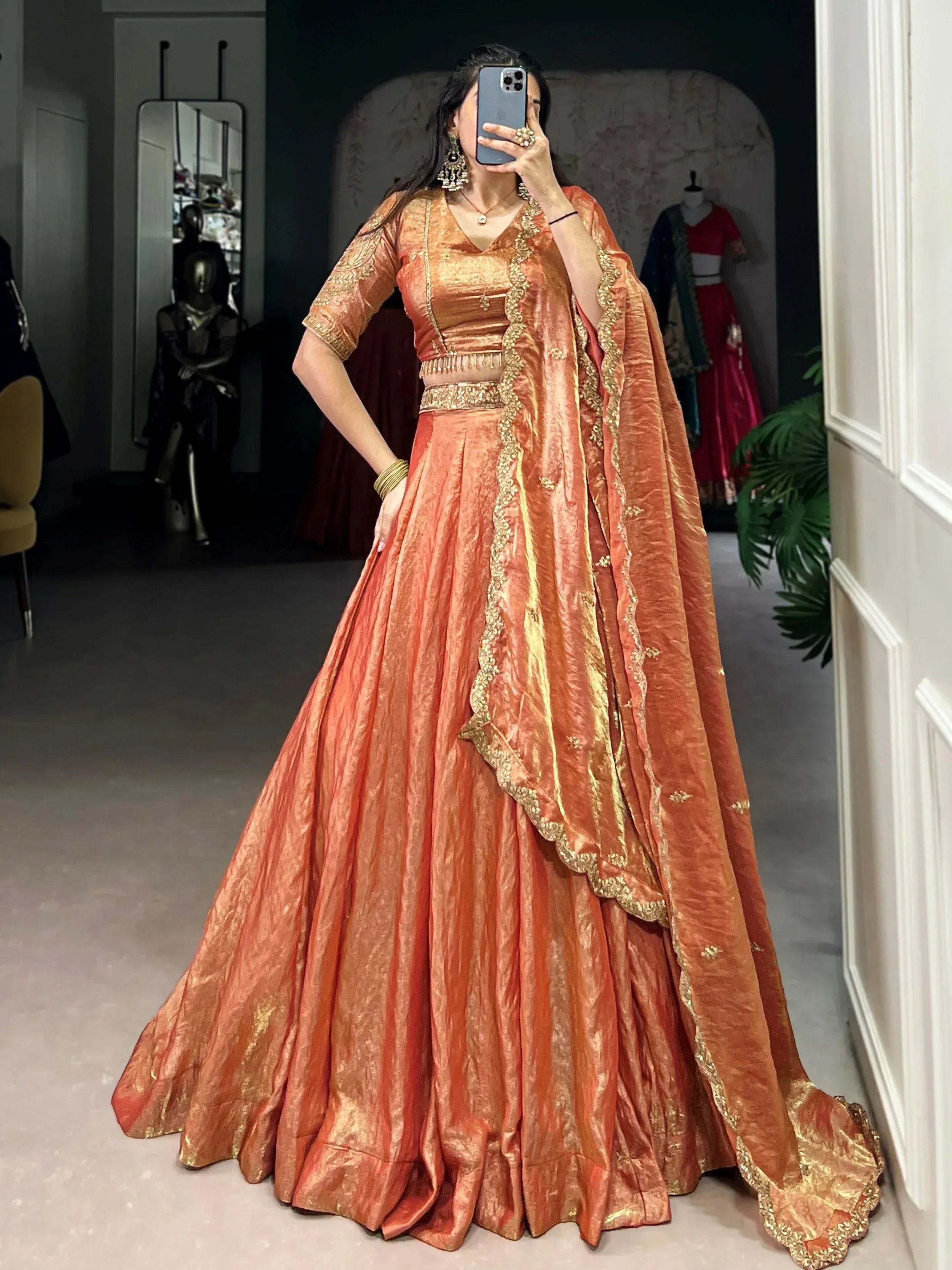 Woman in orange designer lehenga choli with gold embroidery, perfect for Indian ethnic wear events