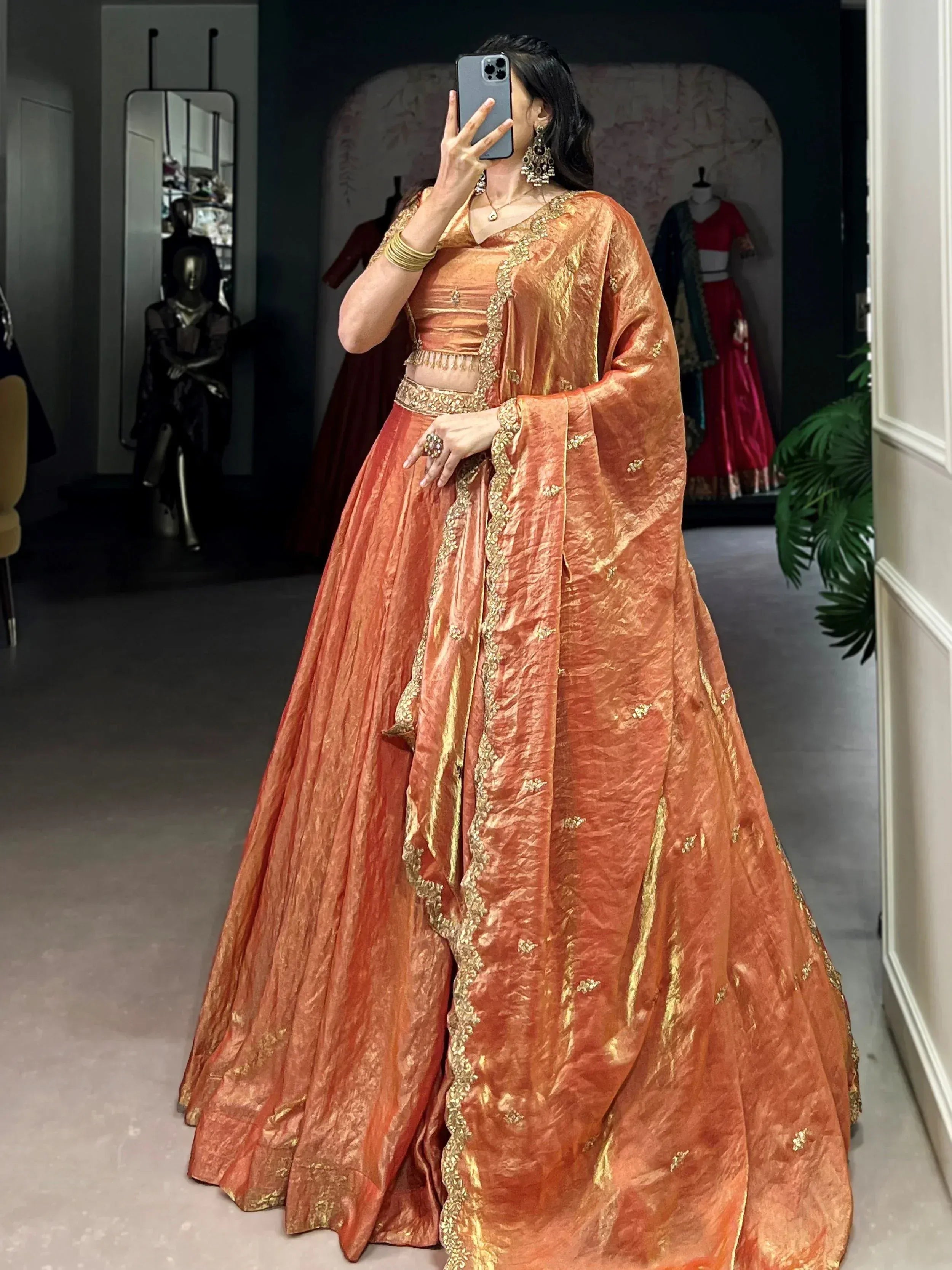 Orange designer lehenga choli with gold embroidery, perfect for Indian weddings and festive occasions.