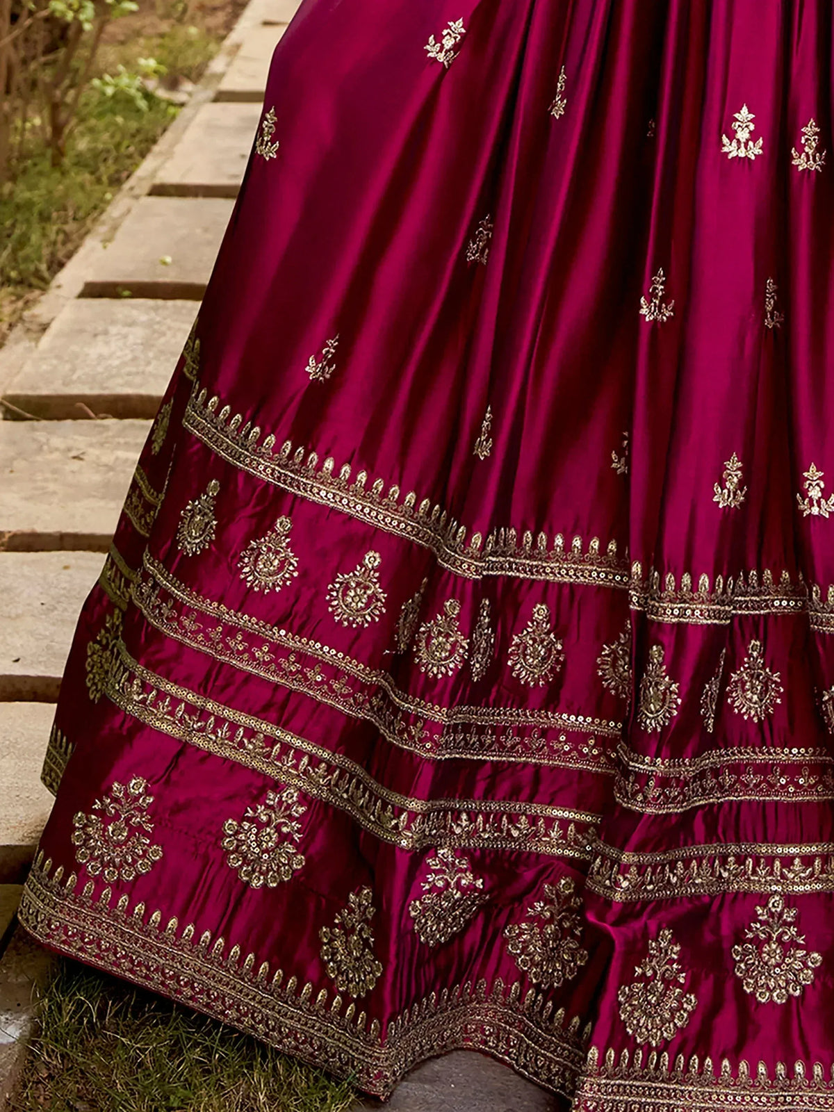 Rich maroon lehenga with intricate gold embroidery and layered borders, perfect for ethnic occasions.