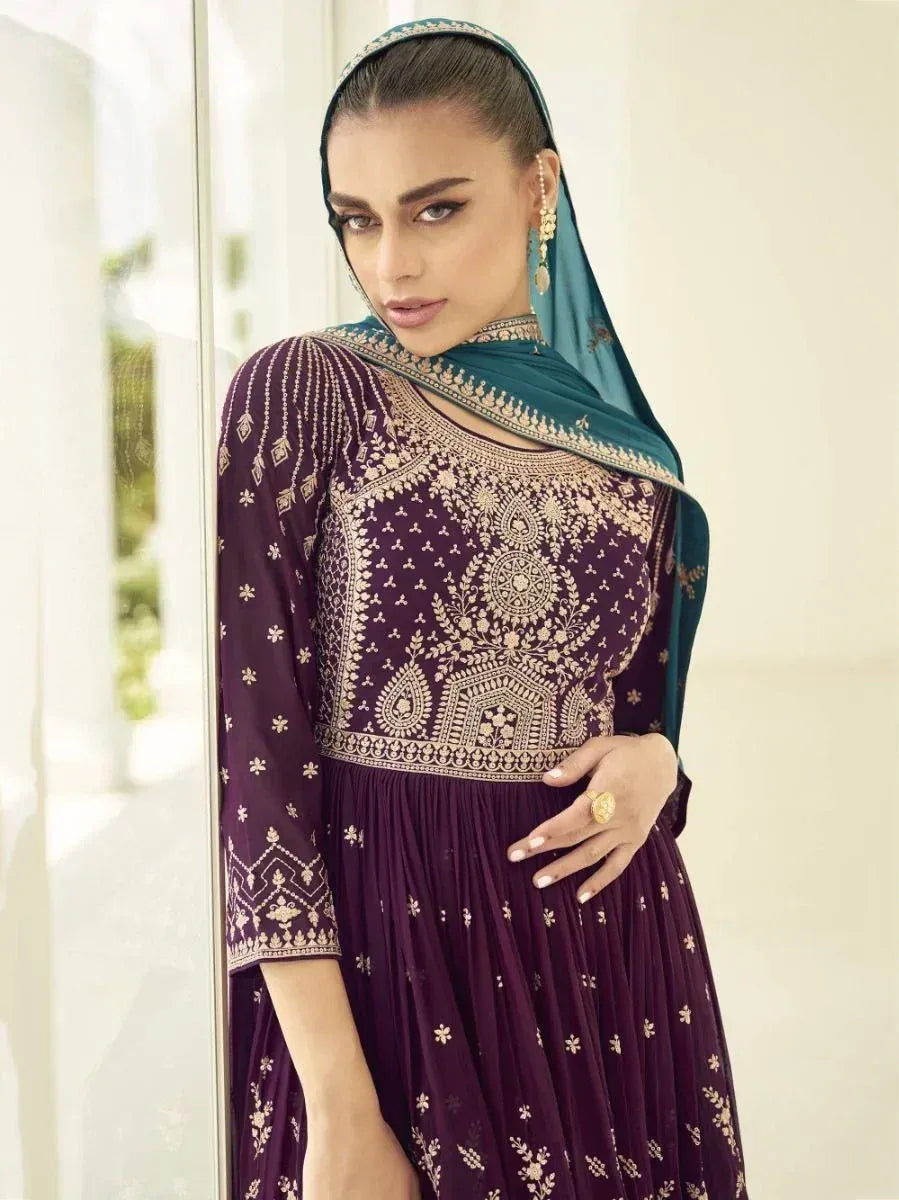 Woman in purple embroidered ethnic gown with blue dupatta and gold jewelry