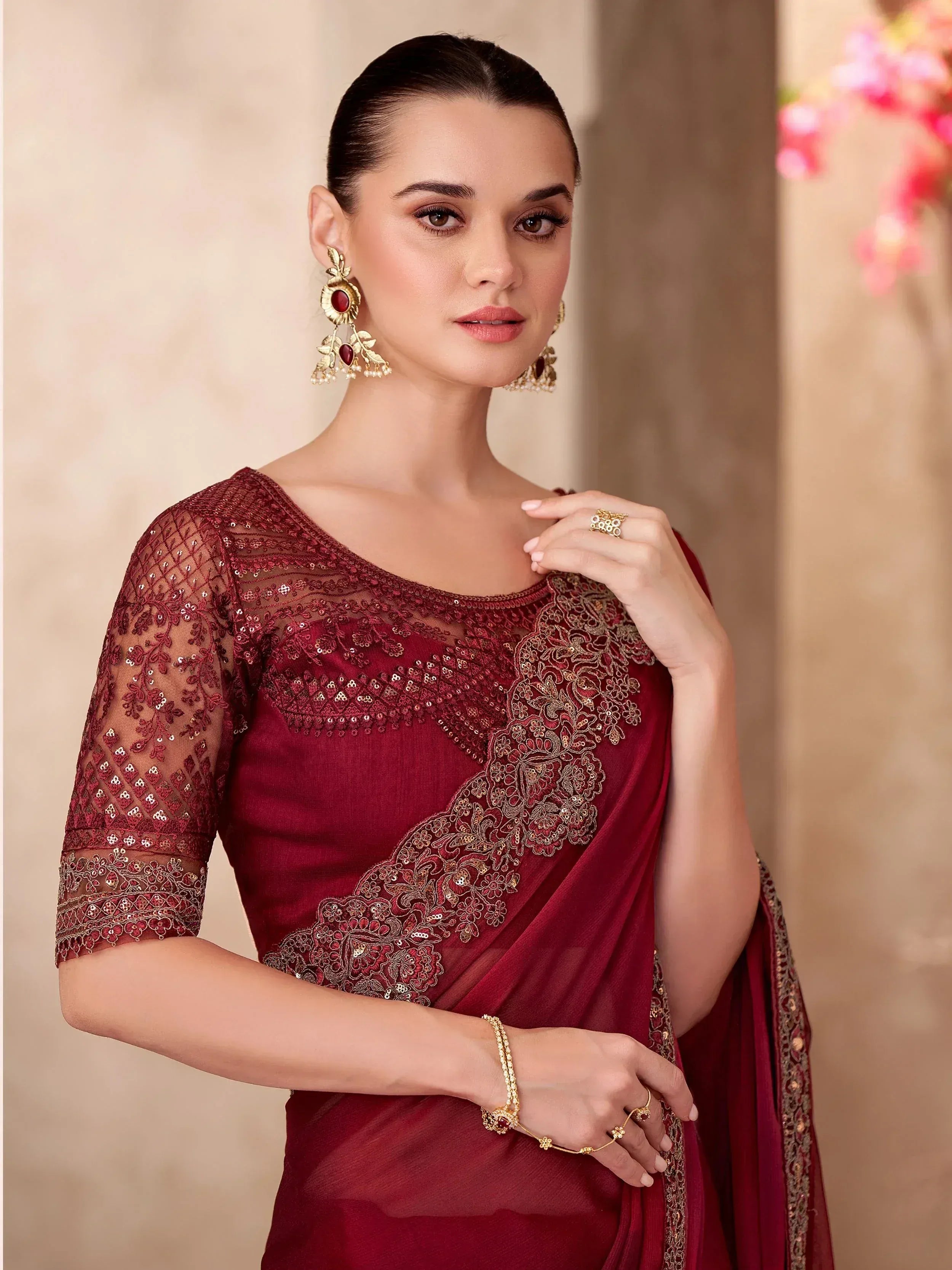 Elegant maroon saree with gold embroidery and sequins, paired with matching blouse and traditional jewelry