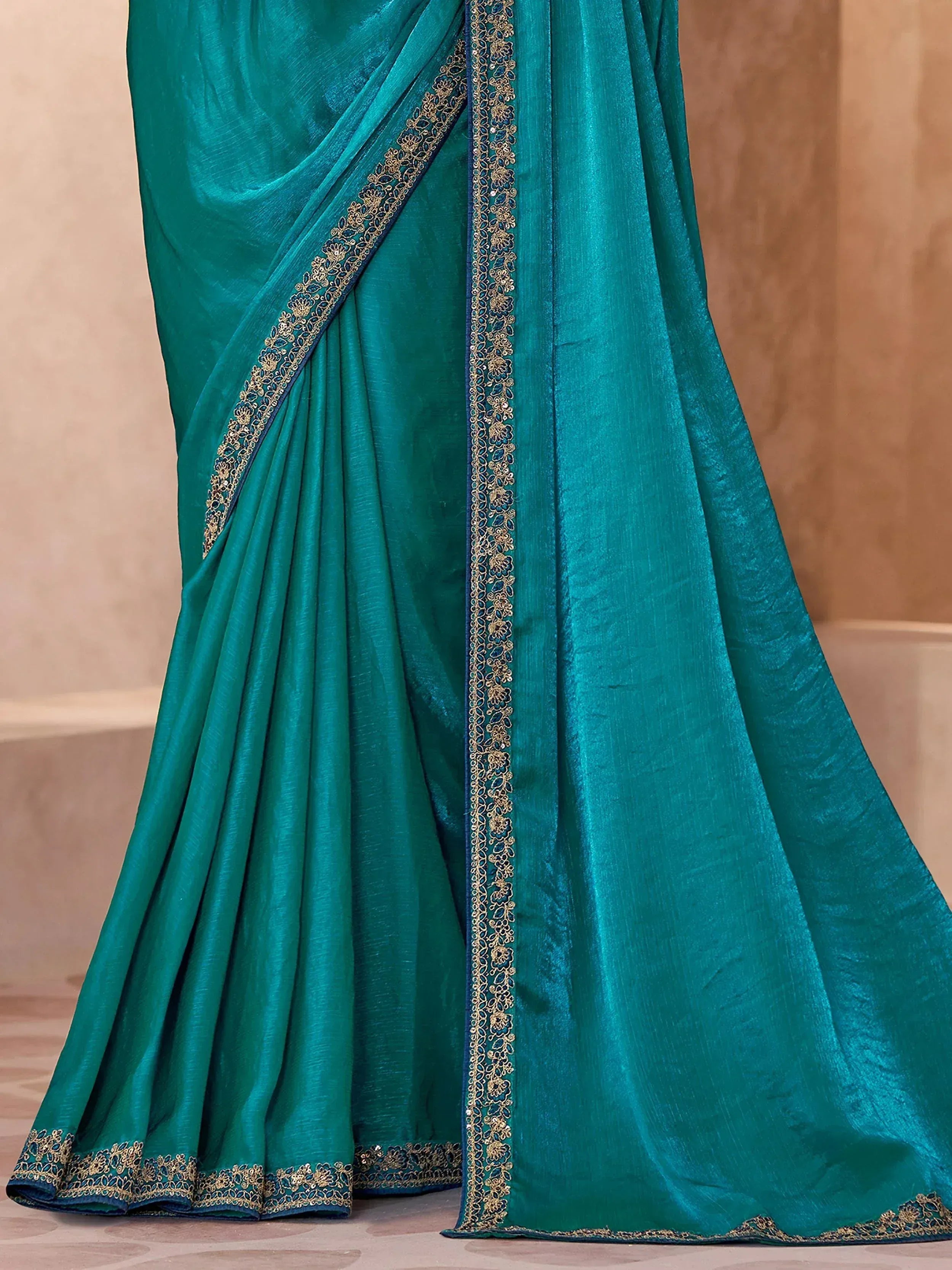 Teal designer saree with gold floral embroidery and blue border, perfect for ethnic wear occasions.