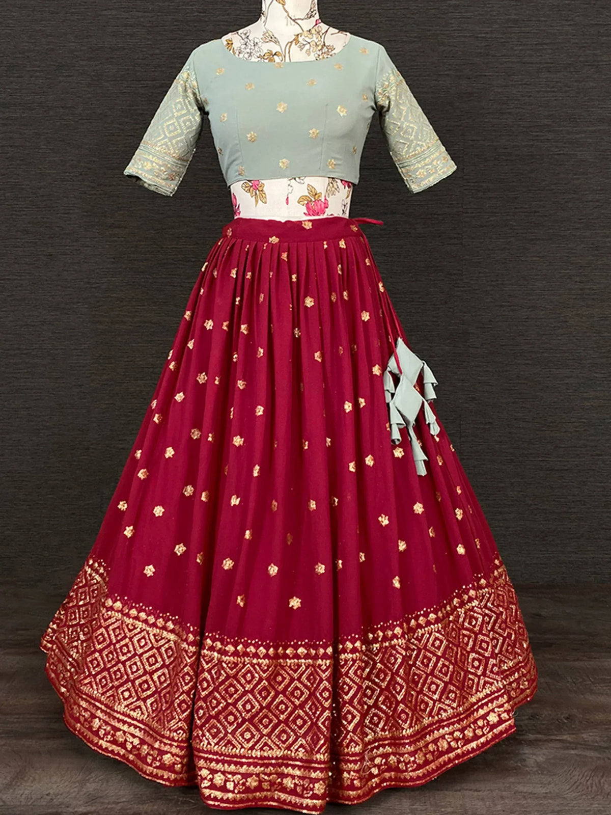 Red and mint green embroidered lehenga choli with gold motifs and pleated skirt, ideal for Indian ethnic wear
