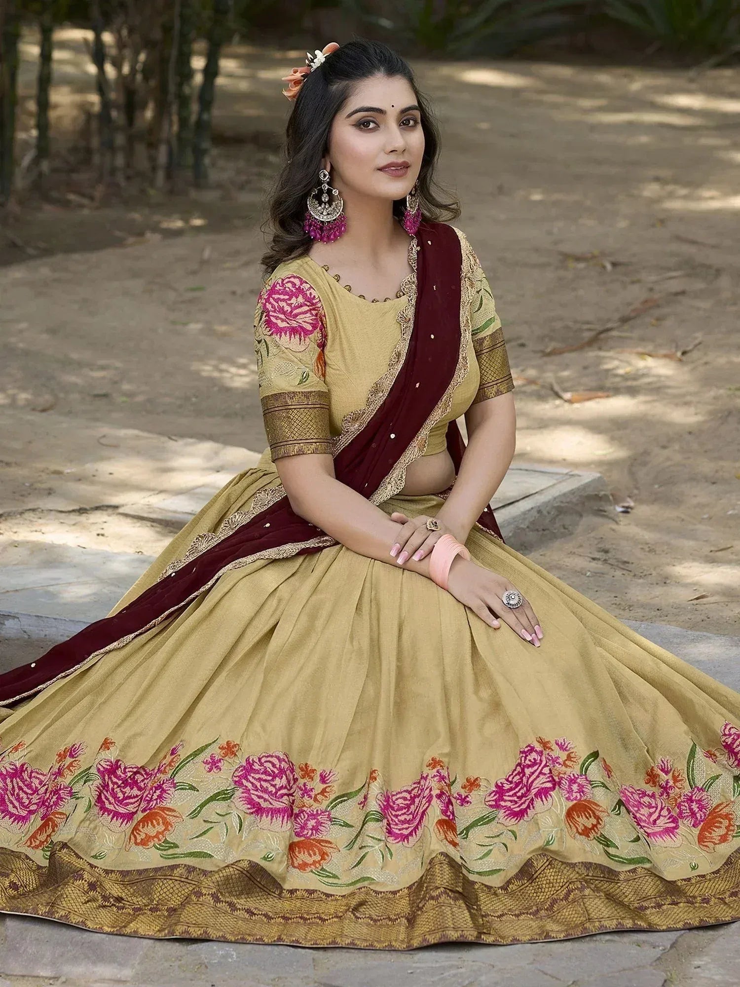 Woman in mustard yellow lehenga choli with pink floral embroidery and maroon dupatta, perfect for Indian ethnic occasions