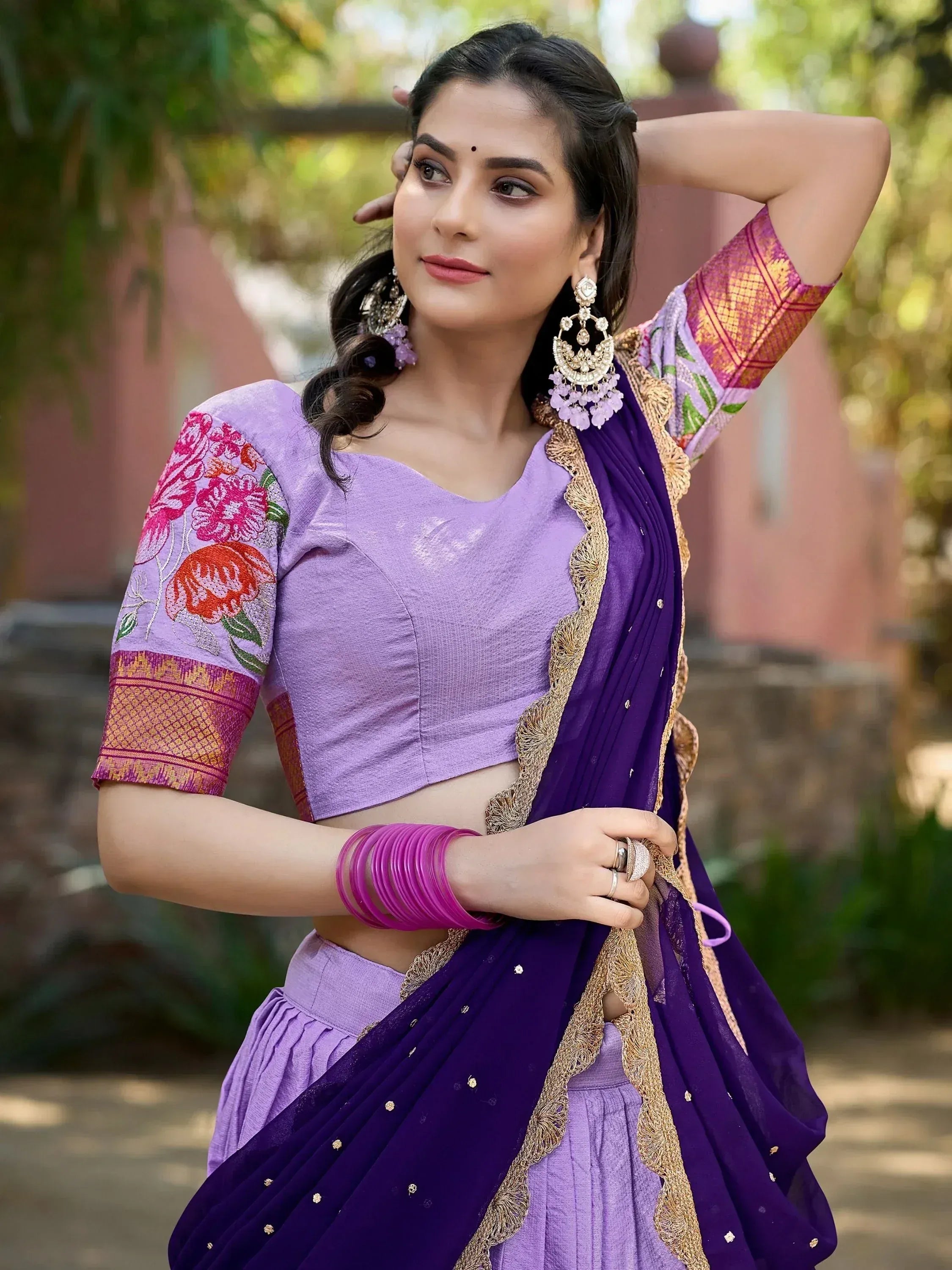 Purple embroidered lehenga choli with floral sleeves and gold border, styled with statement earrings and bangles