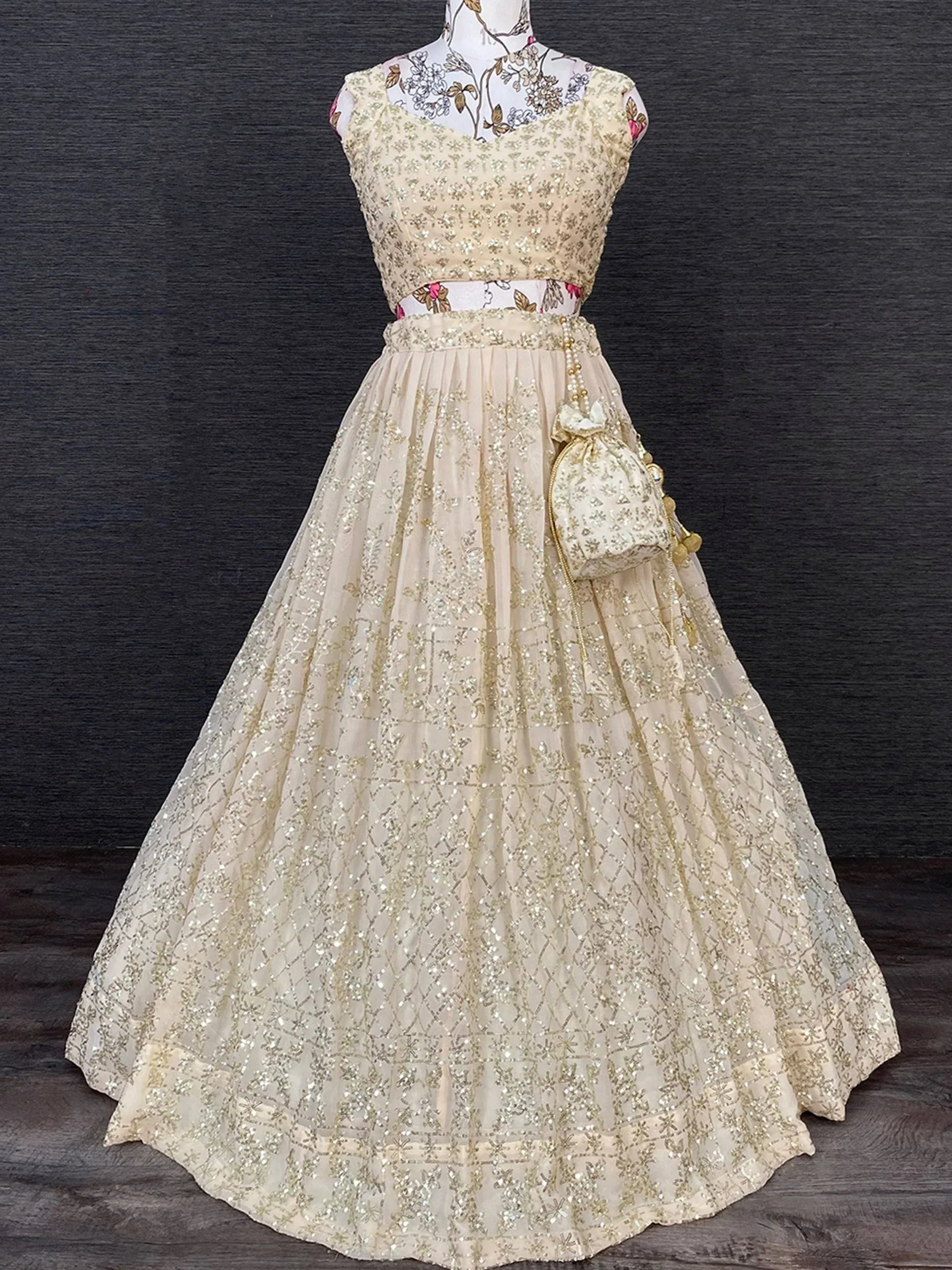 Cream and gold embroidered lehenga choli with matching potli bag, ideal for Indian weddings and festive occasions.