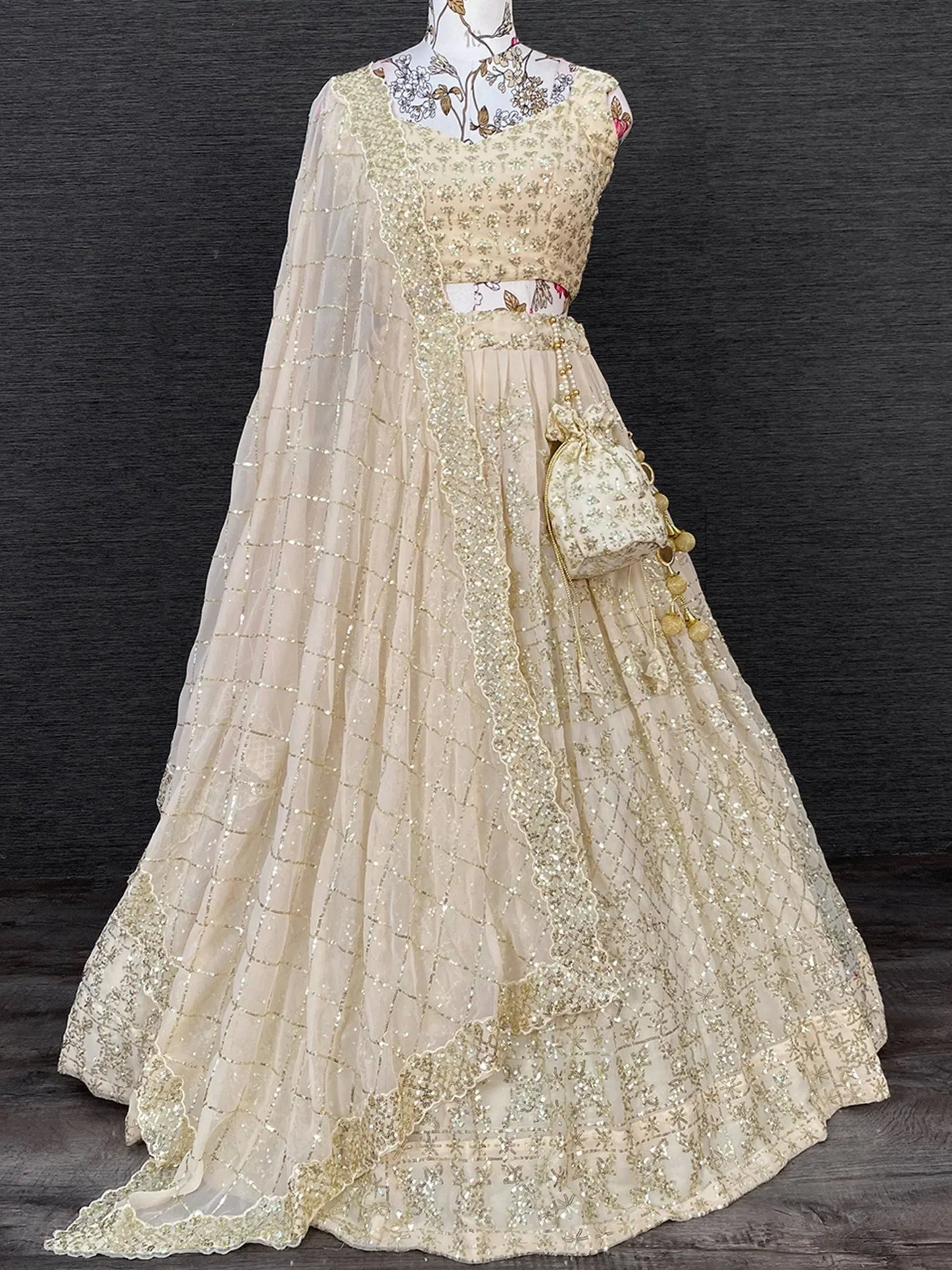 Cream embroidered lehenga choli with gold sequins, sheer dupatta, and matching potli bag for Indian ethnic wear
