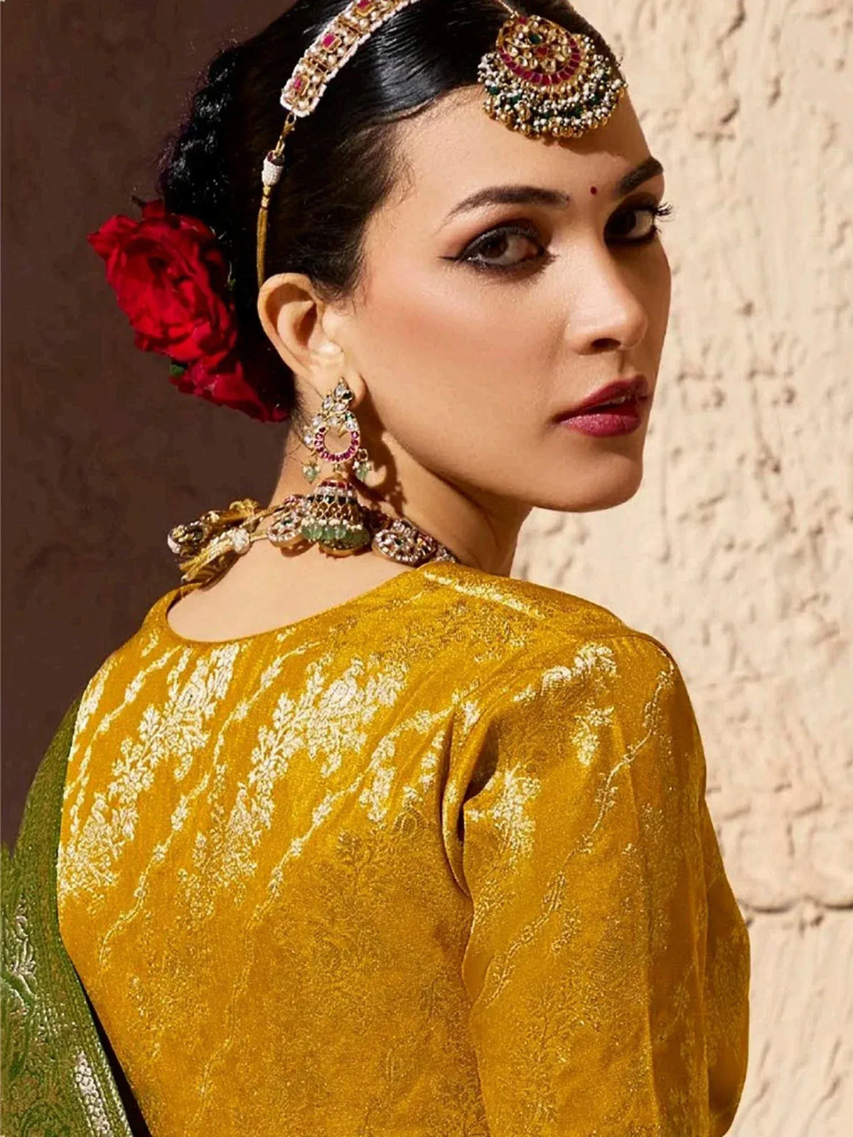 Elegant woman in golden ethnic wear with intricate jewelry and red floral hair accessory