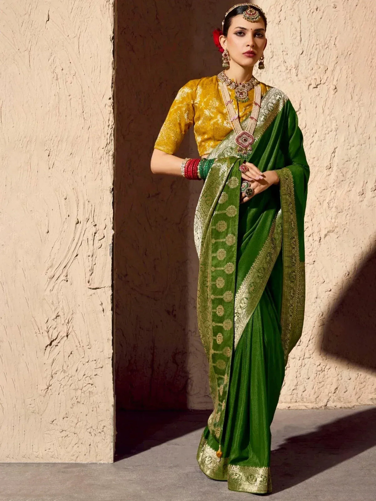 Green silk saree with gold embroidery, paired with a yellow blouse and traditional jewelry