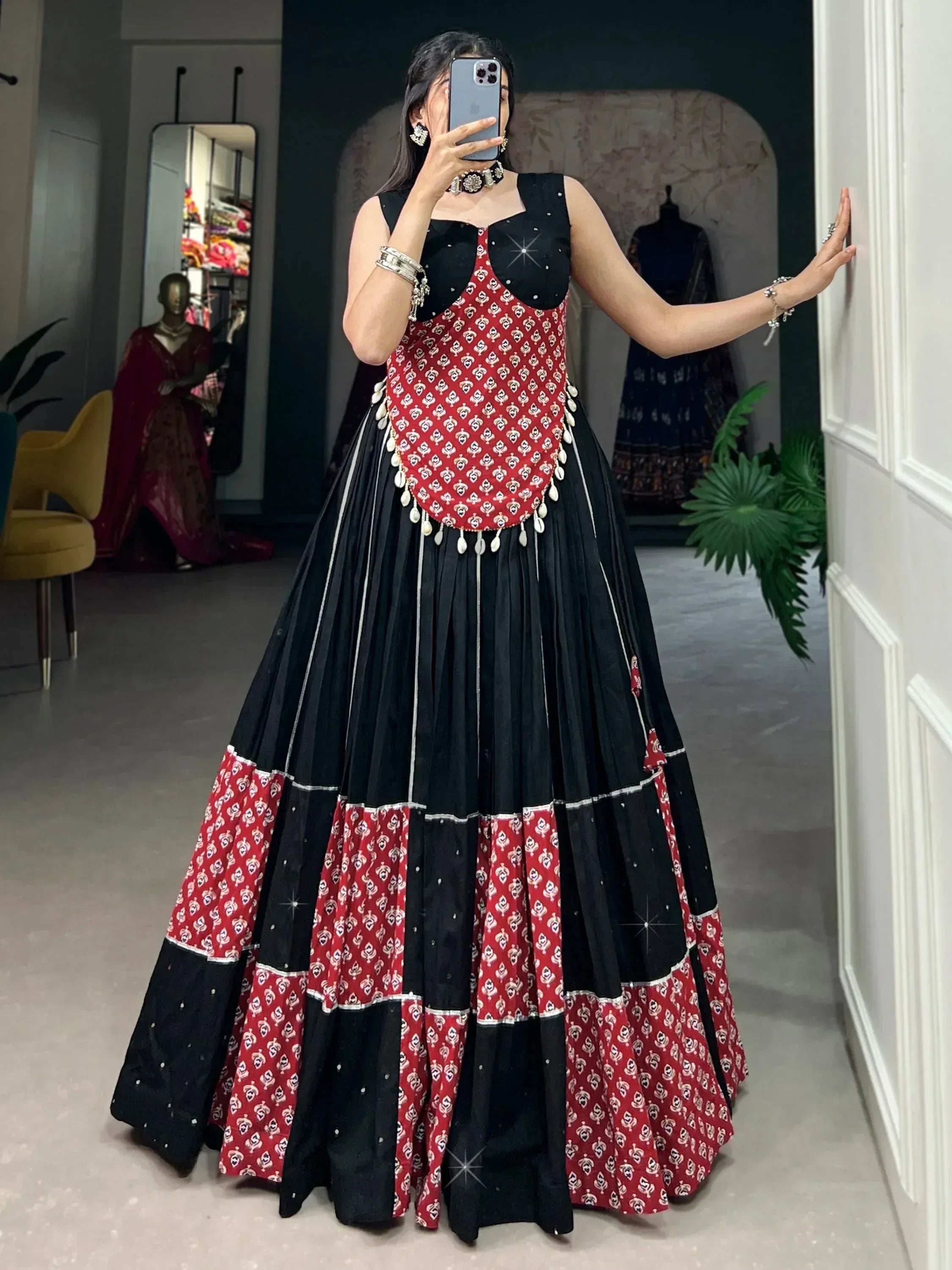 Black and red printed ethnic gown with pleated skirt and mirror work, perfect for festive occasions.