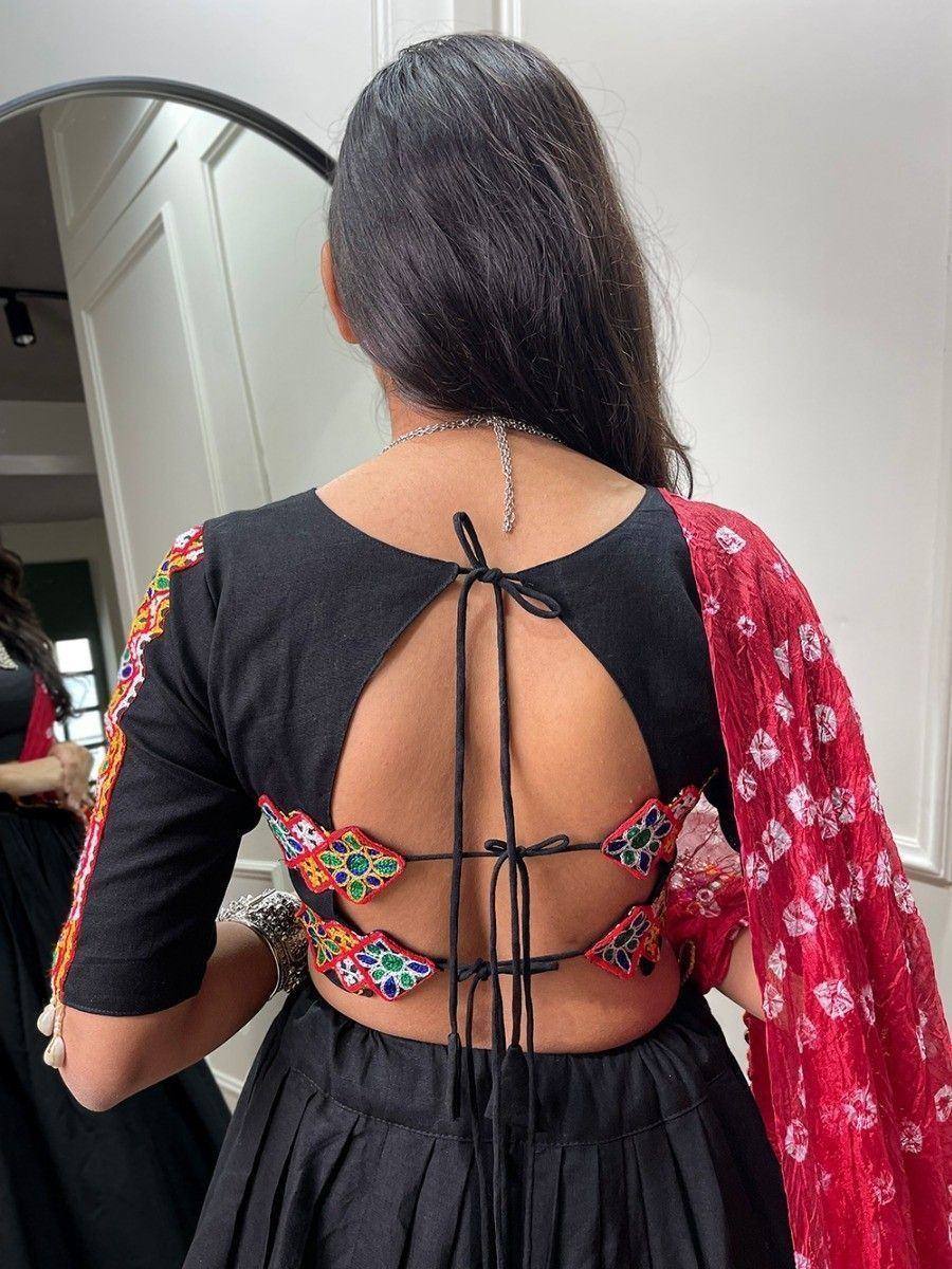 Black backless ethnic top with colorful embroidery and tie-up detail, paired with red floral dupatta