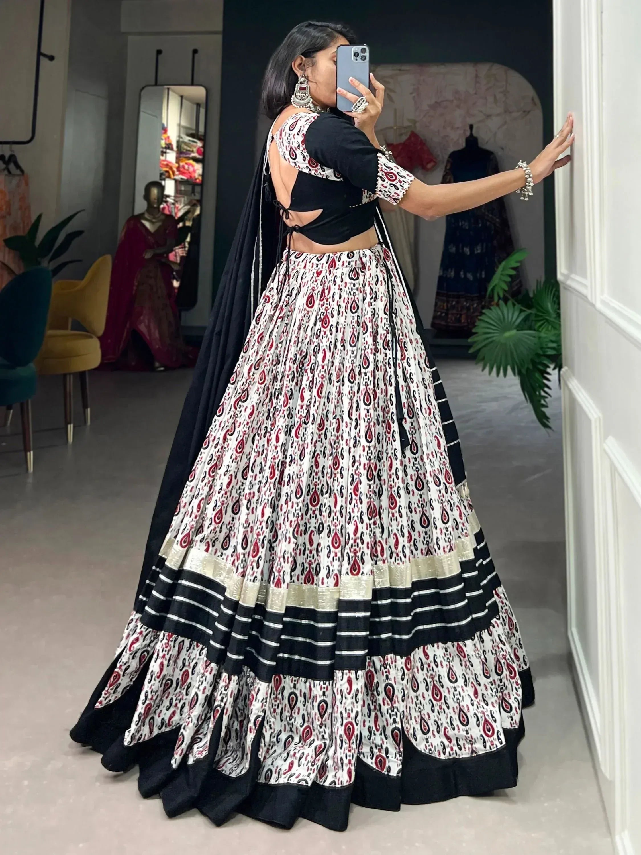 Woman in black and white printed lehenga choli with mirror selfie in boutique