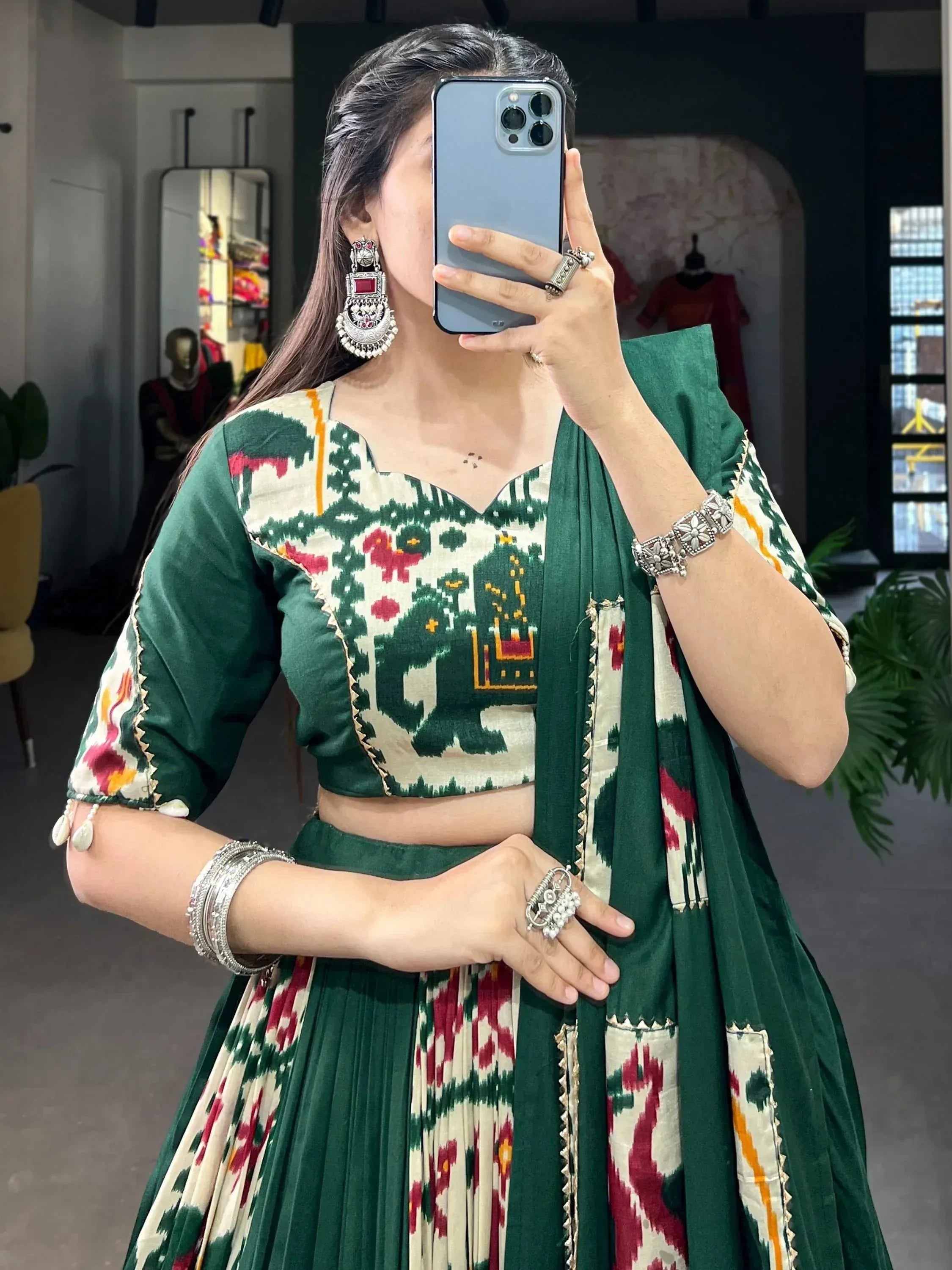 Green and cream ikat print lehenga choli with elephant motifs, paired with silver jewelry for ethnic wear