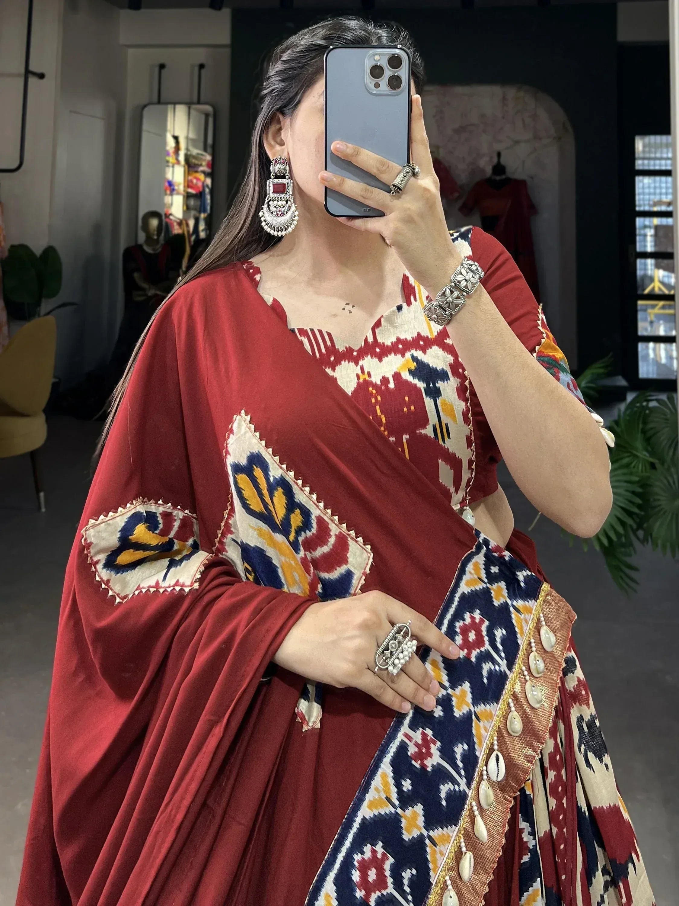 Woman in red ethnic saree with ikat print and silver jewelry, taking mirror selfie