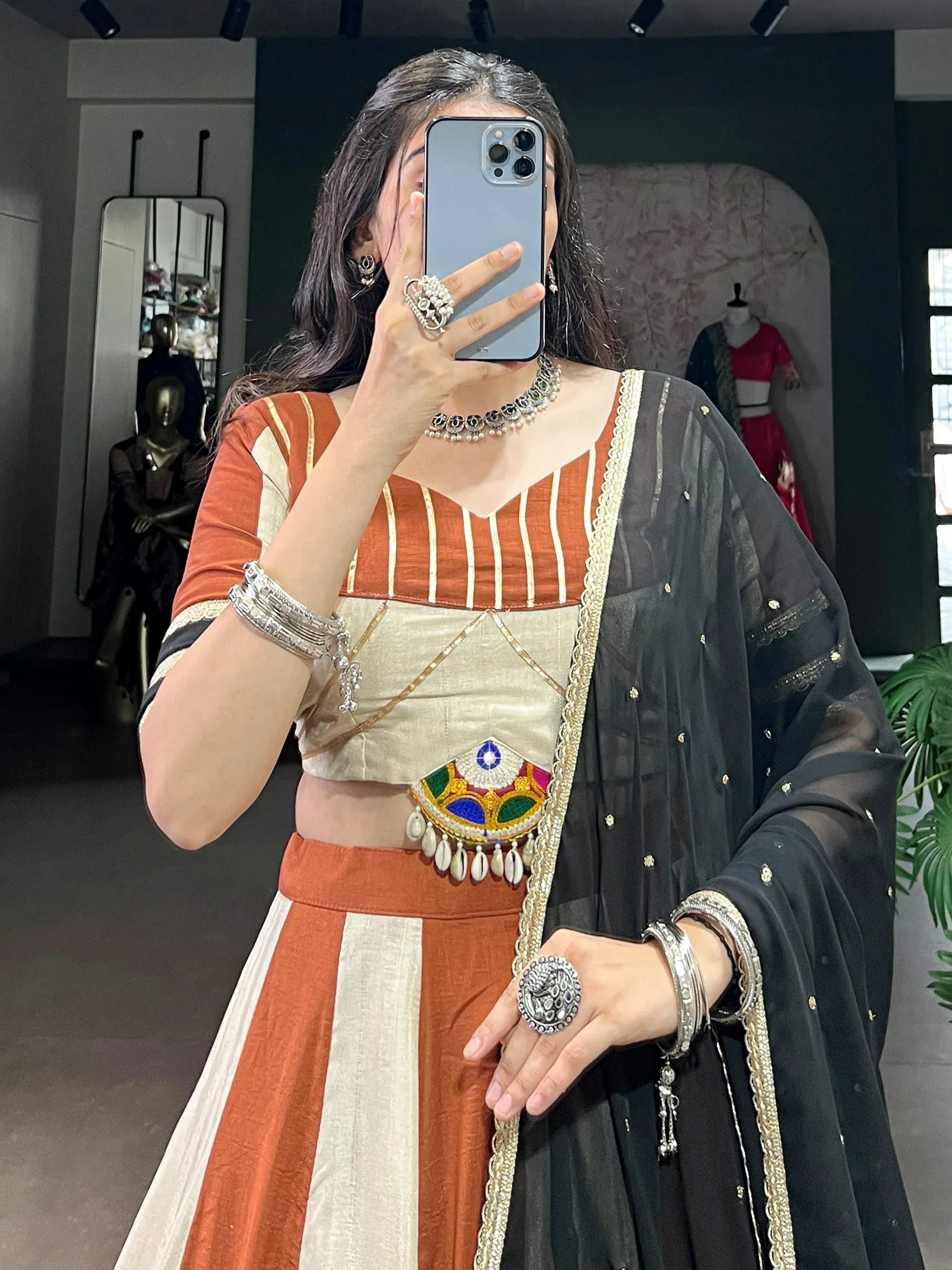 Woman in orange and cream striped lehenga choli with black dupatta, traditional Indian ethnic wear