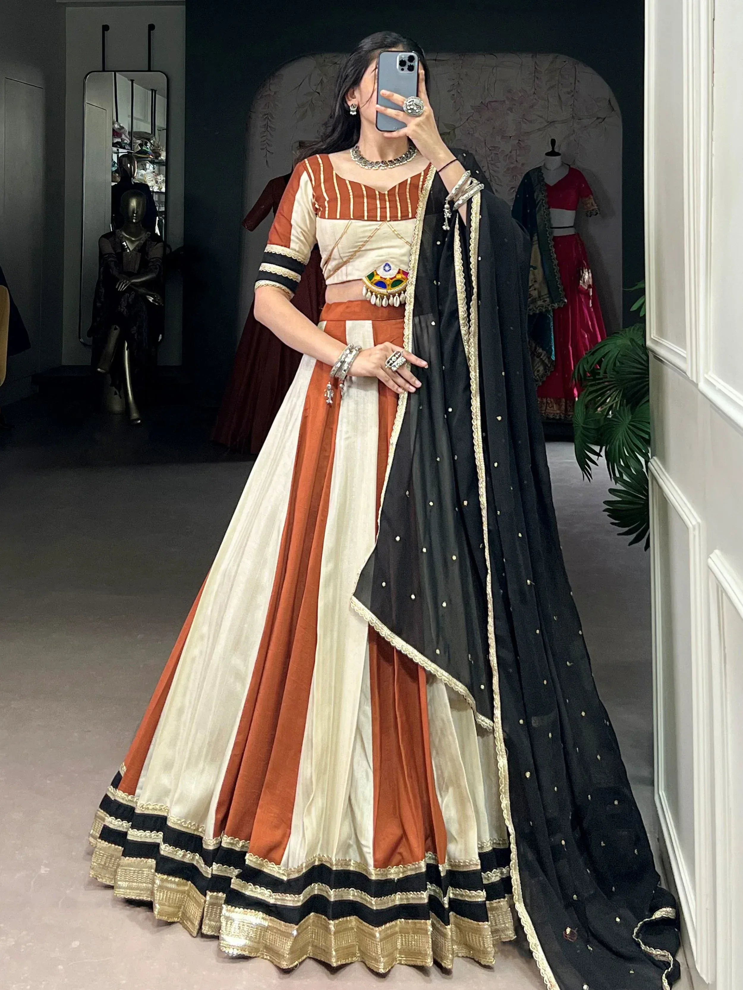 Woman in orange and cream striped lehenga choli with black dupatta, ethnic Indian wear