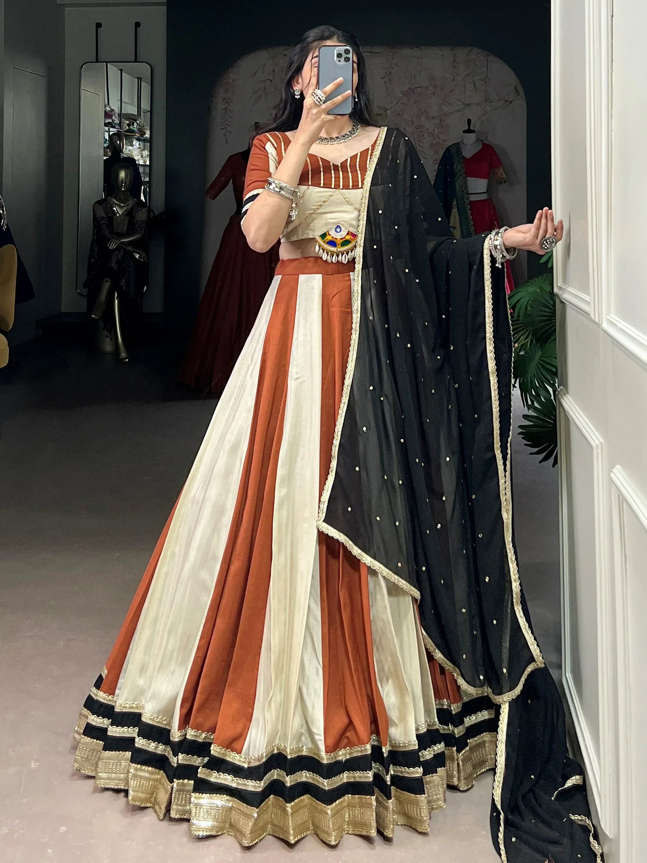 Woman in orange and cream striped lehenga choli with black dupatta, ethnic Indian wear