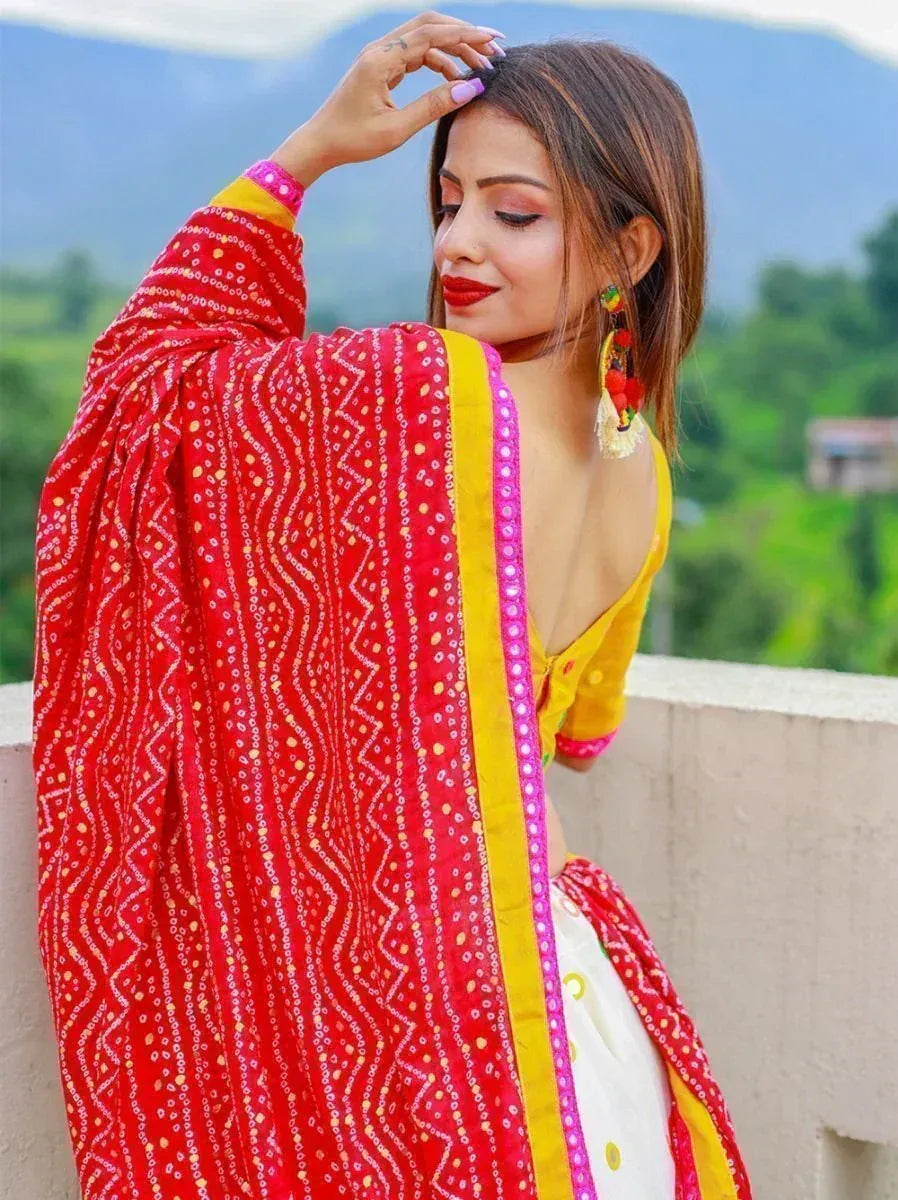 Woman in vibrant red and yellow ethnic salwar kameez with mirror work, mountain backdrop