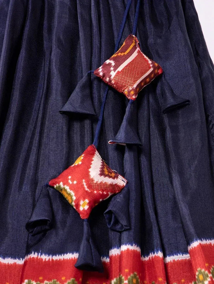 Navy blue ethnic gown with red ikat border and matching patterned pouches, perfect for Indian festive wear.