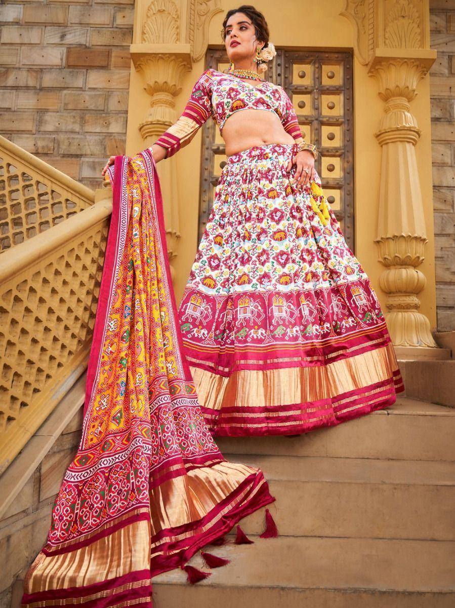 Woman in vibrant Indian lehenga choli with elephant print, standing on palace steps