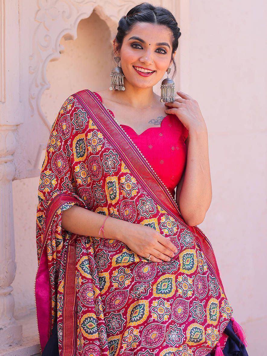 Woman in vibrant red printed saree with floral motifs, paired with pink blouse and jhumka earrings, ideal for ethnic occasions