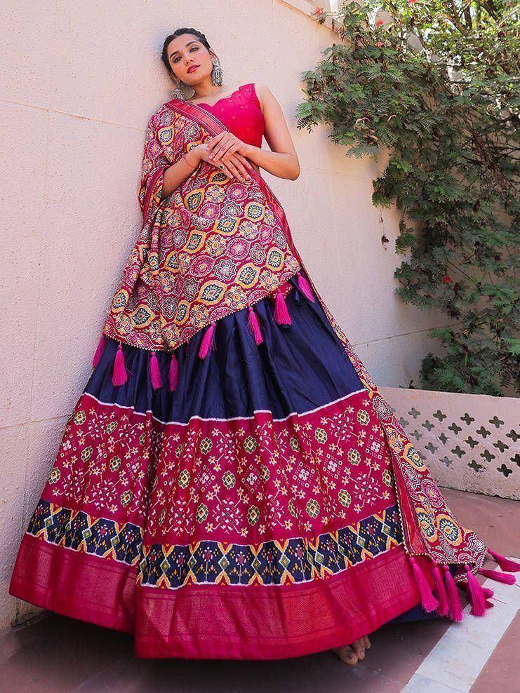 Woman in vibrant pink and navy blue designer lehenga choli with intricate embroidery and tassels, perfect for Indian ethnic wear.