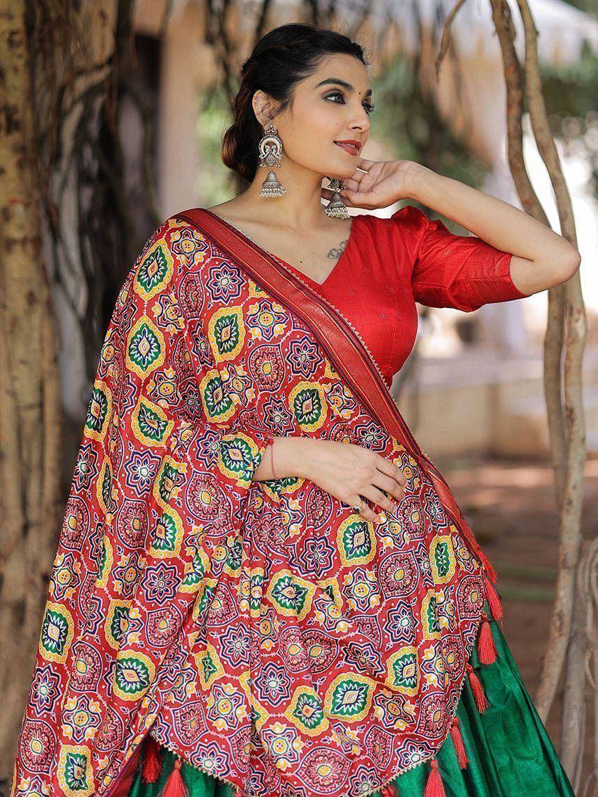 Vibrant red and green printed saree with floral motifs, paired with a red blouse, perfect for ethnic occasions.